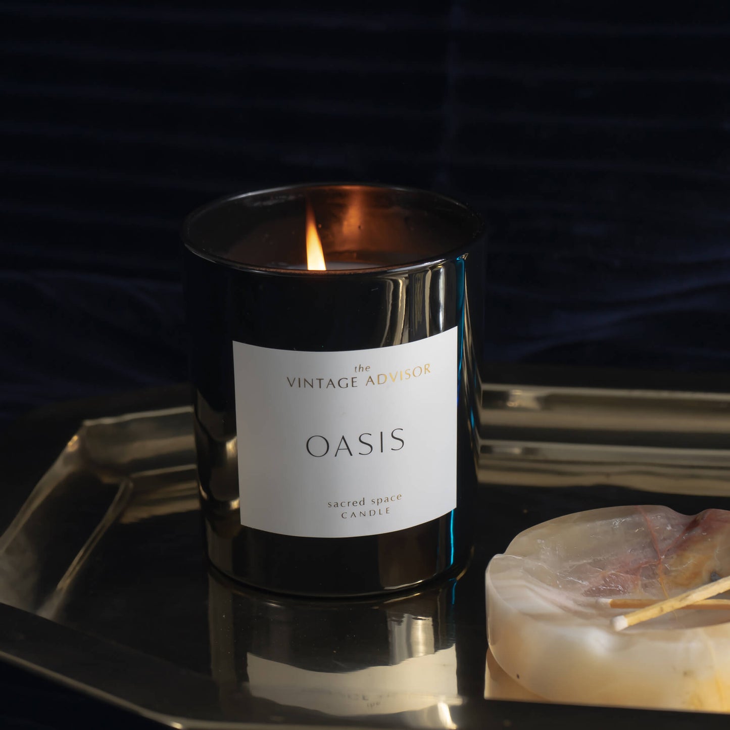 Oasis sacred space candle lit on top of a gold brass tray
