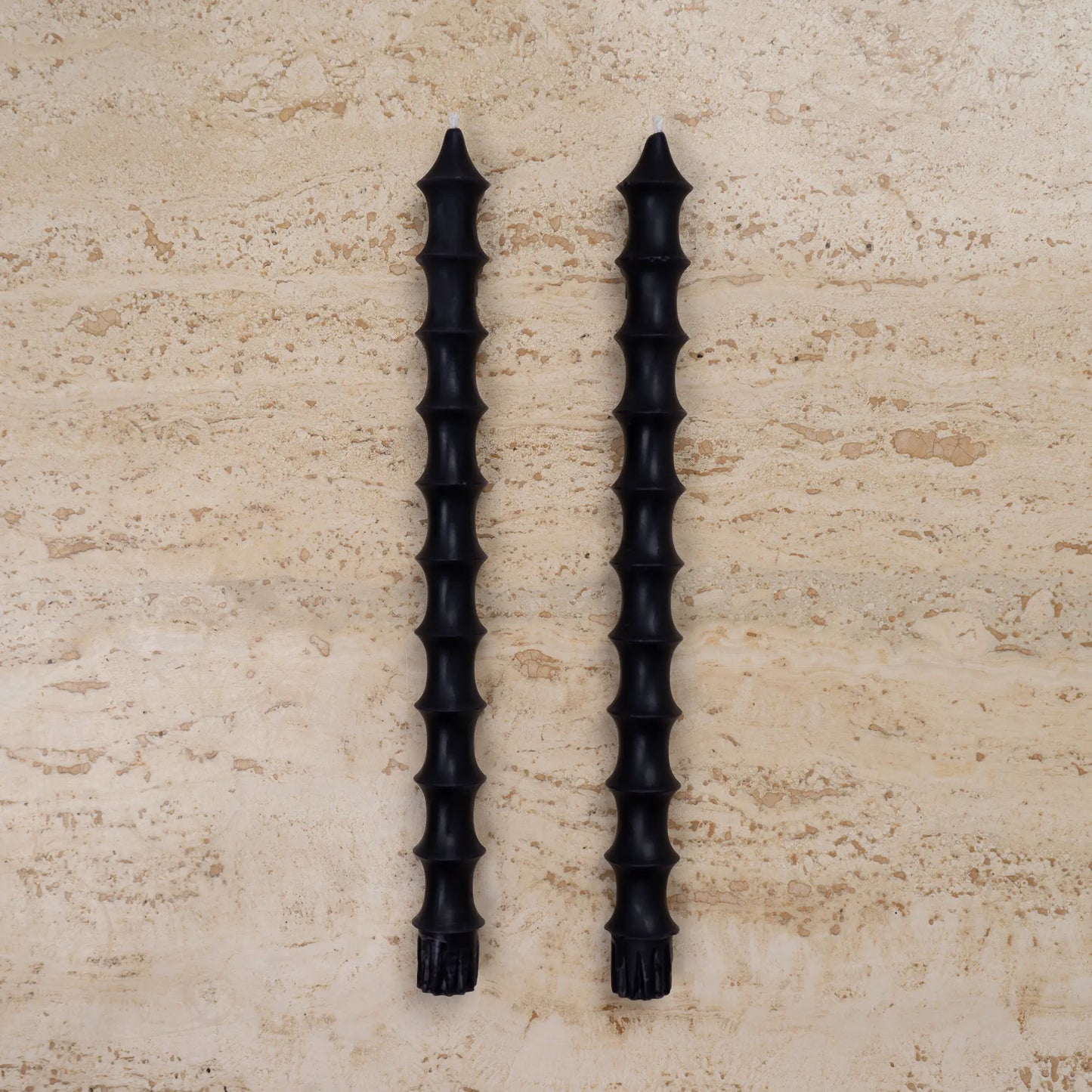 Hand-poured bamboo pagoda beeswax taper candles in midnight blackcolor, set of two on travertine surface