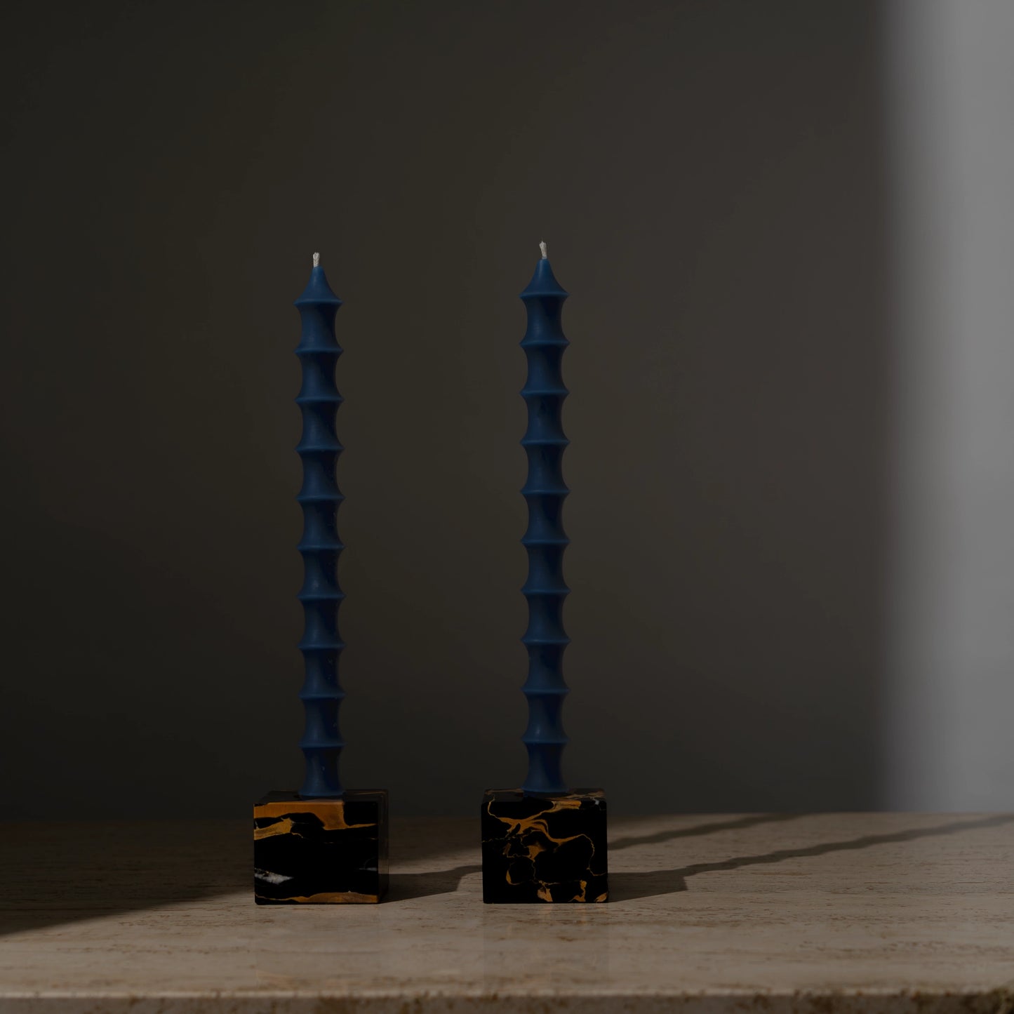 Hand-poured bamboo pagoda-shaped beeswax taper candles in lucid blue color, set of two in vintage black marble candleholders with gold veining