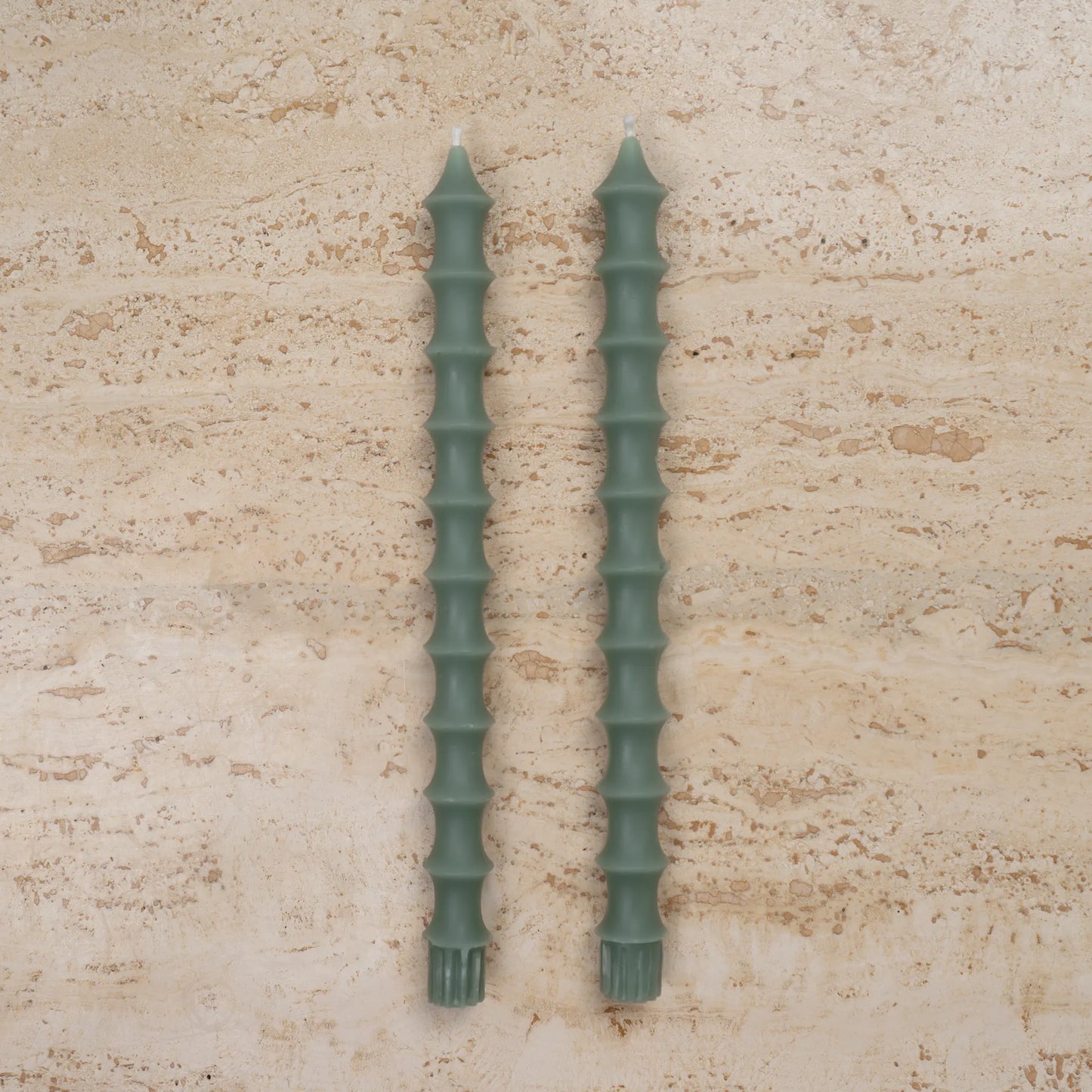 Hand-poured bamboo pagoda beeswax taper candles in jasper green color, set of two on travertine surface