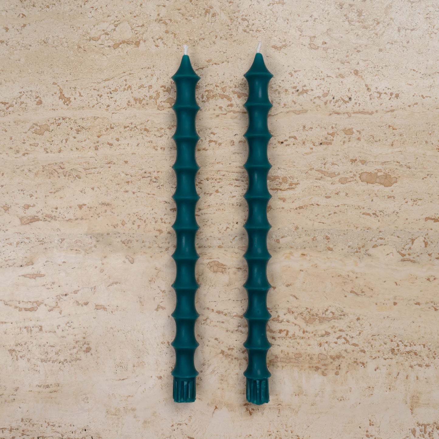 Hand-poured bamboo pagoda beeswax taper candles in peacock green color, set of two on travertine surface