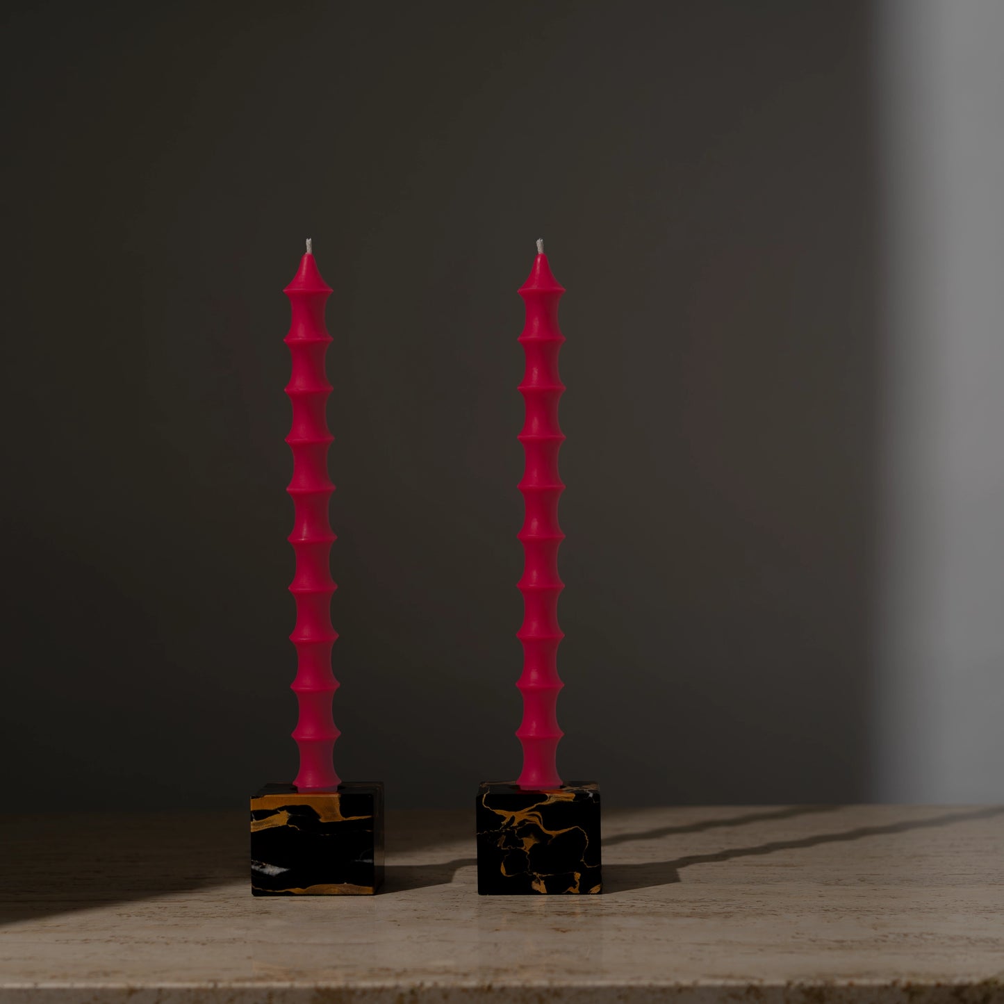 Hand-poured bamboo pagoda-shaped beeswax taper candles in dragonfruit pink color, set of two in vintage black marble candleholders with gold veining