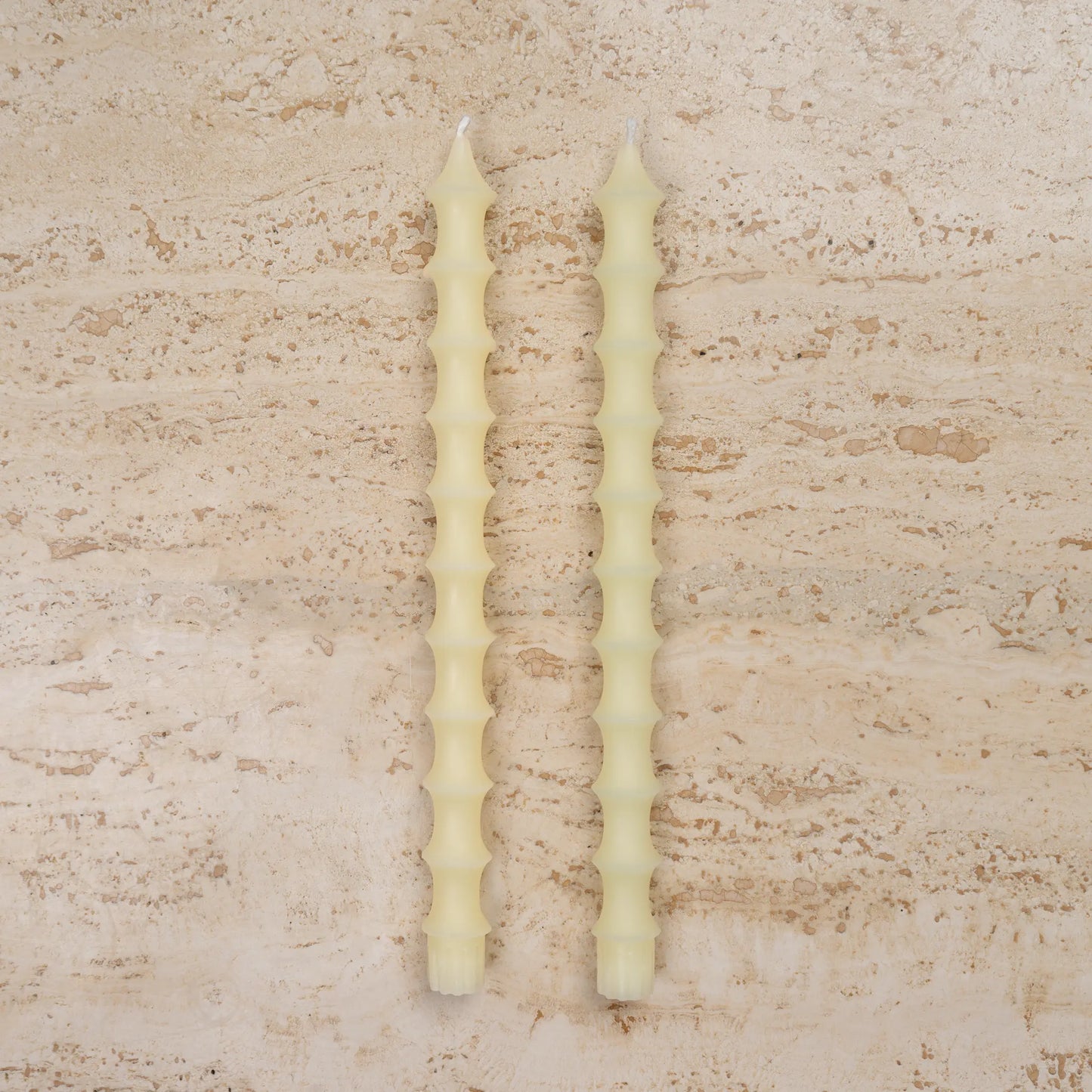 Hand-poured bamboo pagoda beeswax taper candles in alabaster white color, set of two on travertine surface