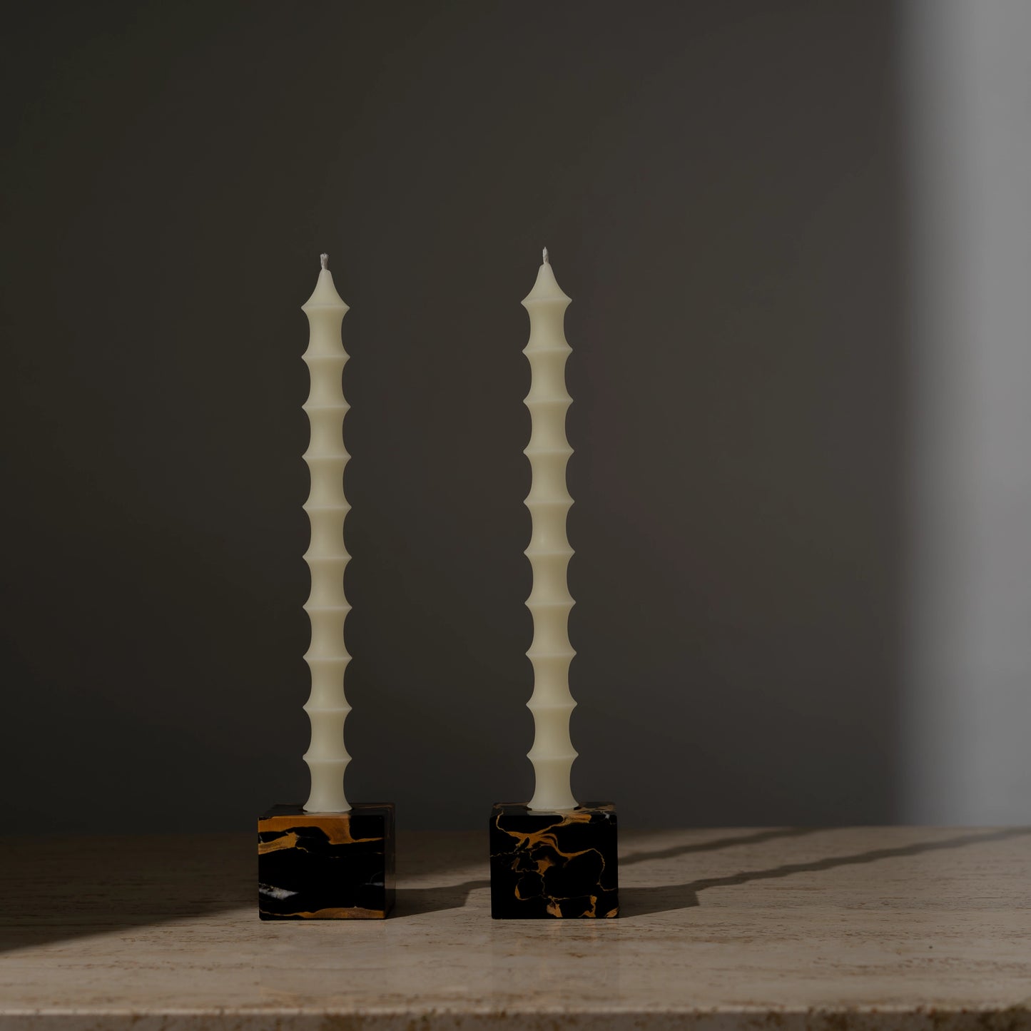 Hand-poured bamboo pagoda-shaped beeswax taper candles in alabaster white color, set of two in vintage black marble candleholders with gold veining