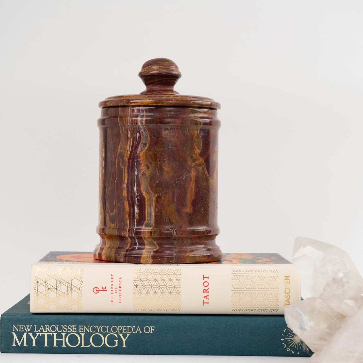 Vintage red onyx stone jar with lid showing rich oxblood and brown natural veining styled on top of vintage books