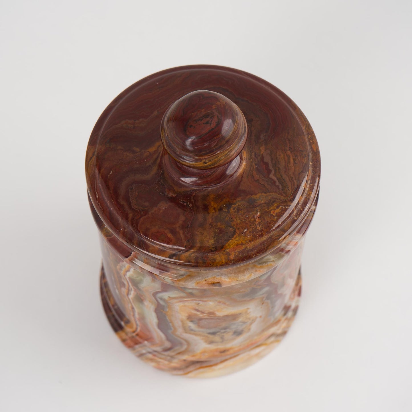 Close-up of red onyx stone lidded jar texture with natural brown veining patterns