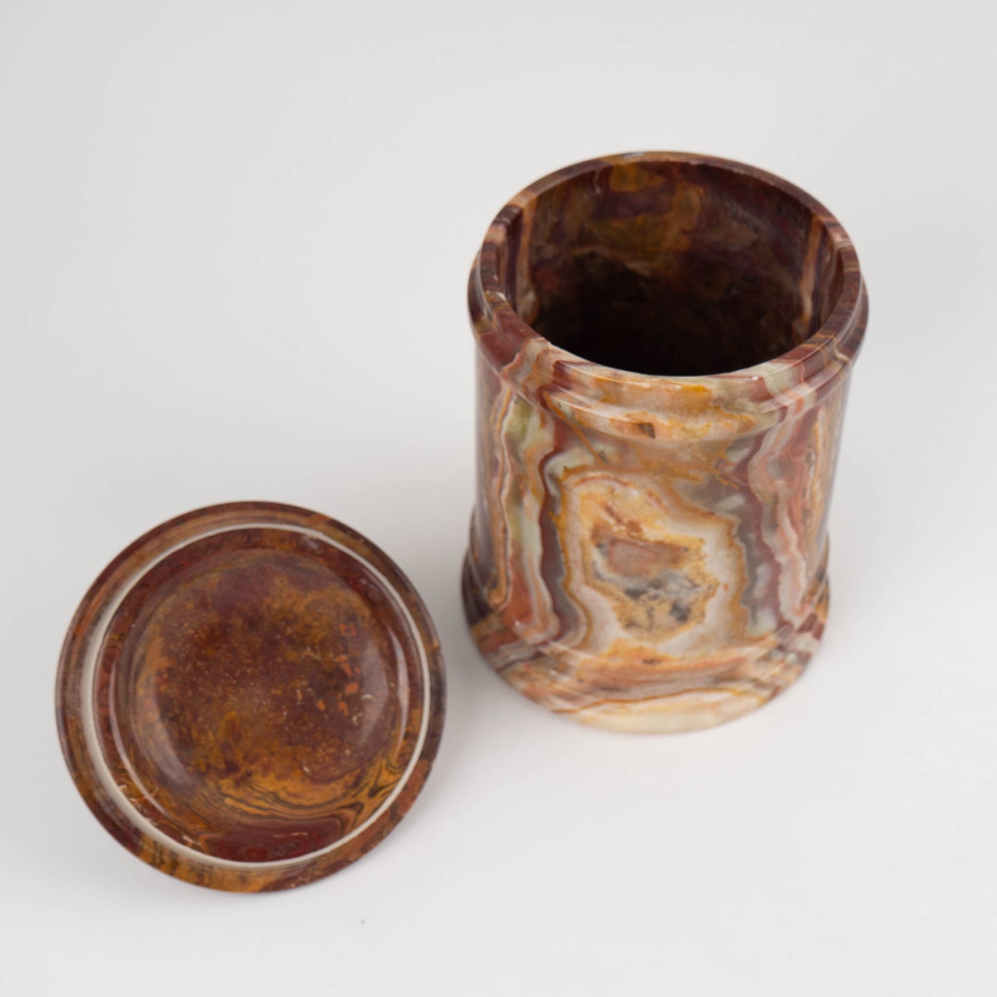 Vintage red onyx stone jar with lid showing rich oxblood and brown natural veining