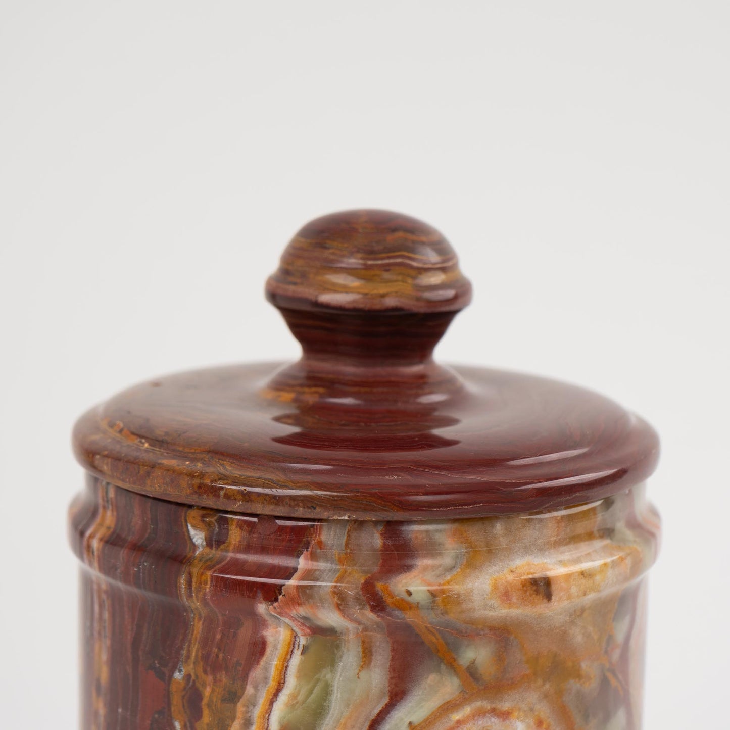 Close-up of red onyx stone jar lid with natural brown veining patterns
