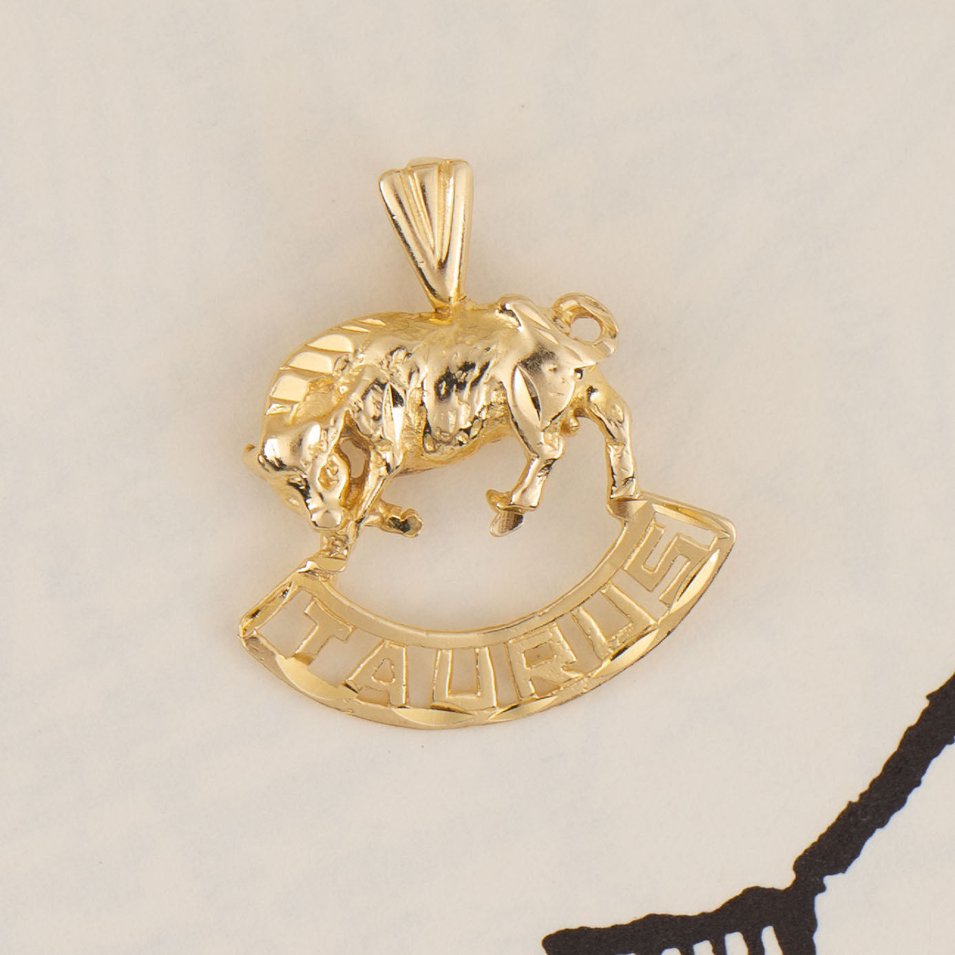 Vintage 14k yellow gold Taurus charm with 3D bull design and Taurus text, showing front and back with 14K hallmark