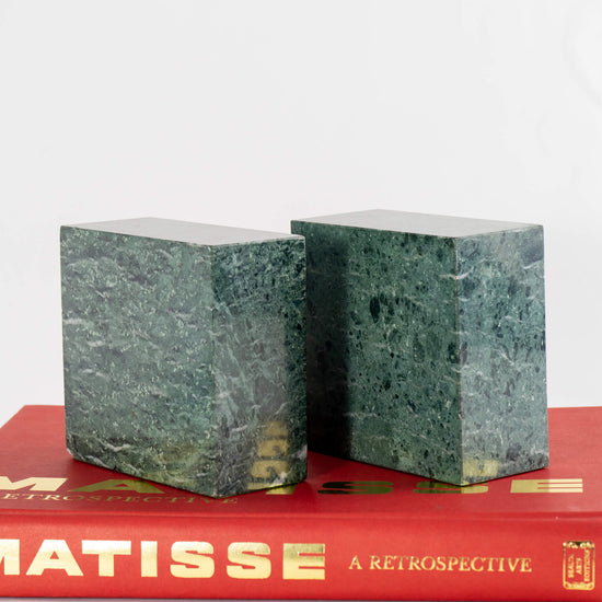 green marble bookends on top of red coffee table book