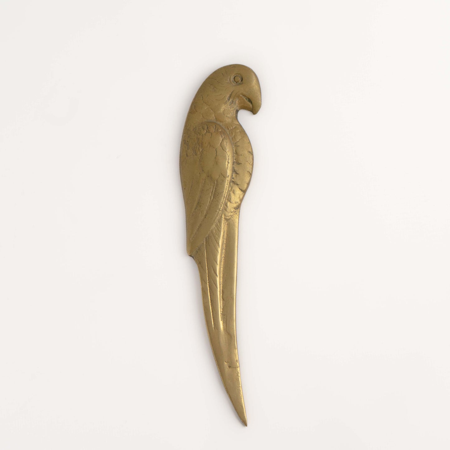 Vintage brass letter opener shaped like a parrot with detailed feather texture and curved beak, circa 1960s-1970s