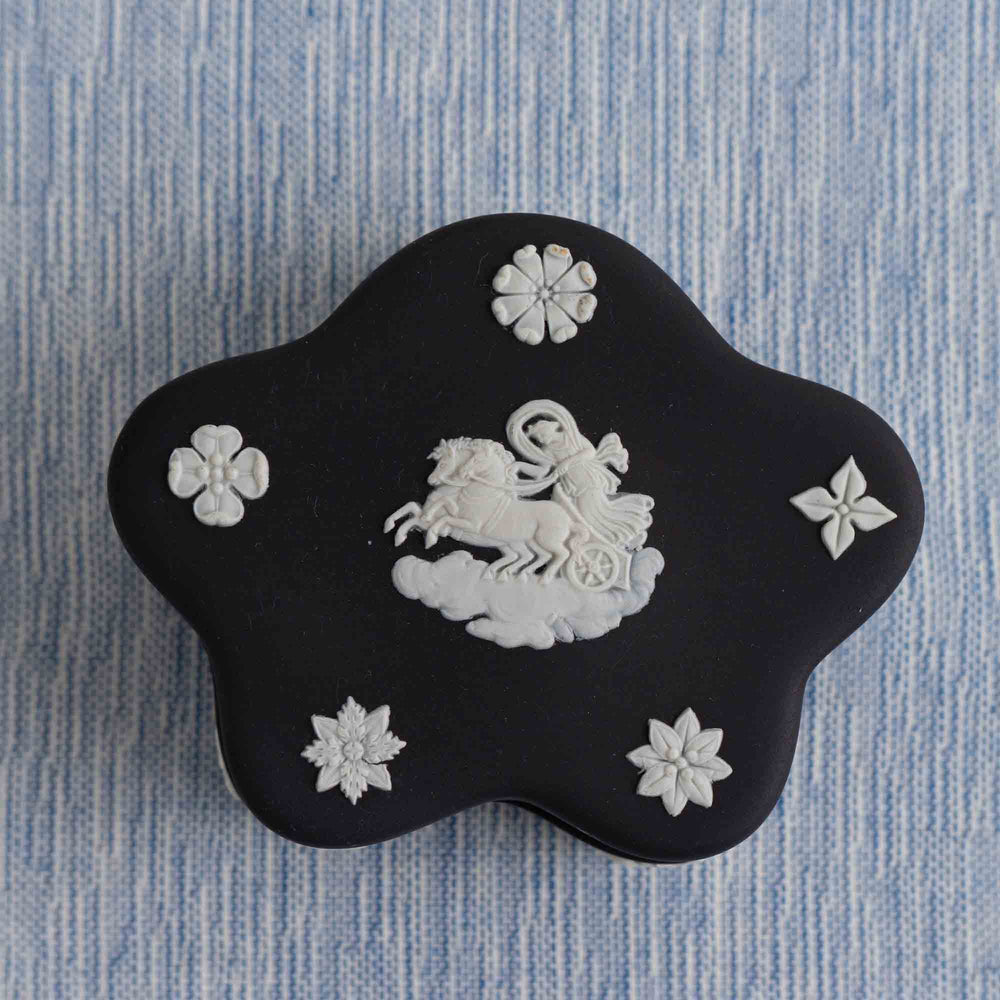 
                  
                    Vintage star-shaped Wedgwood black jasperware trinket box with white relief of Aurora Goddess of Dawn and cherub motifs, 1970s collectible.
                  
                