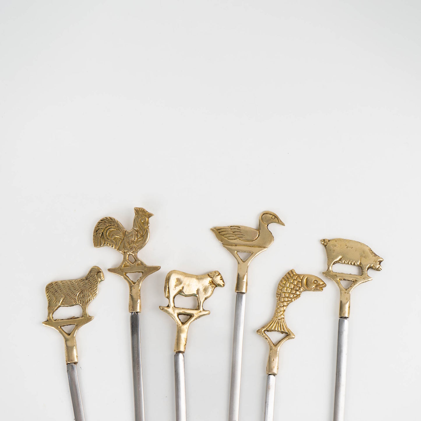 Set of six vintage brass animal barbecue skewers with stainless steel blades, featuring sheep, rooster, cow, duck, fish, and pig handles from the 1960s-70s