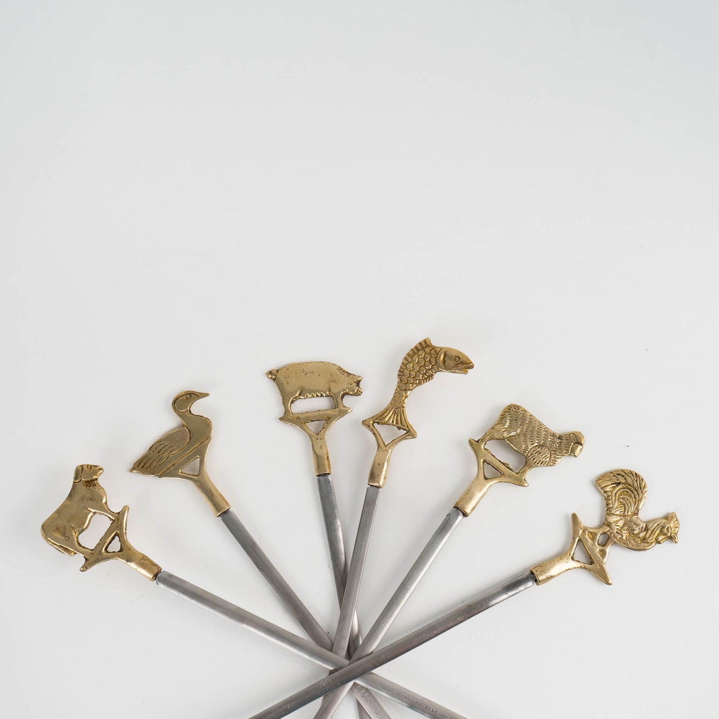 Set of six vintage brass animal barbecue skewers with stainless steel blades, featuring sheep, rooster, cow, duck, fish, and pig handles from the 1960s-70s