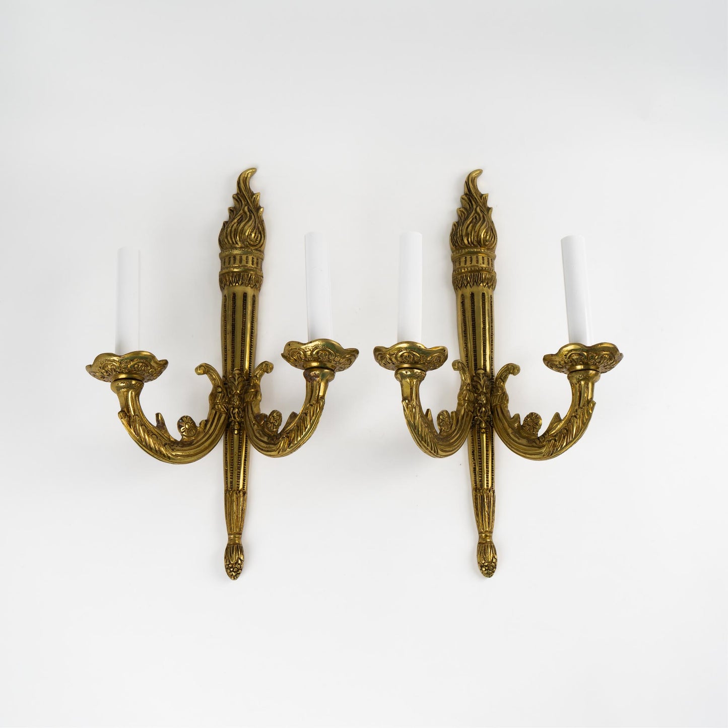 Pair of vintage brass wall sconces in ornate Louis XV style with decorative scrollwork and dual bulb holders, mounted against neutral wall