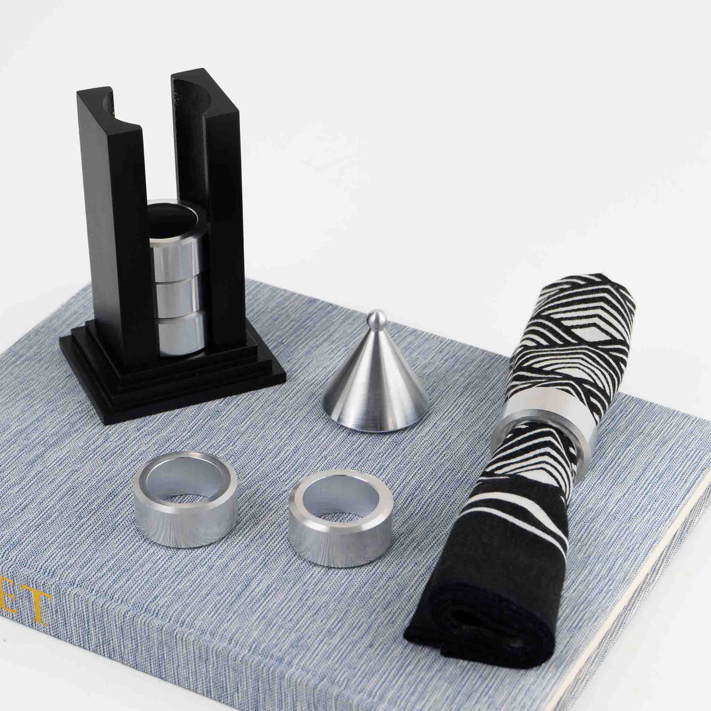 Vintage black building-shaped napkin ring holder displaying six silver metal napkin rings for elegant table setting storage