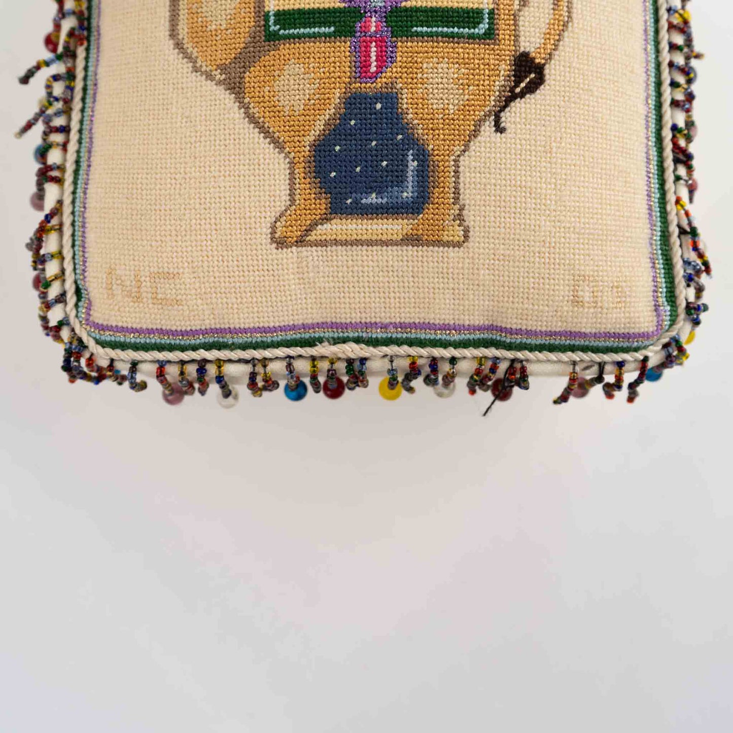 Vintage square needlepoint pillow with hand-stitched camel design and decorative beaded trim around edges