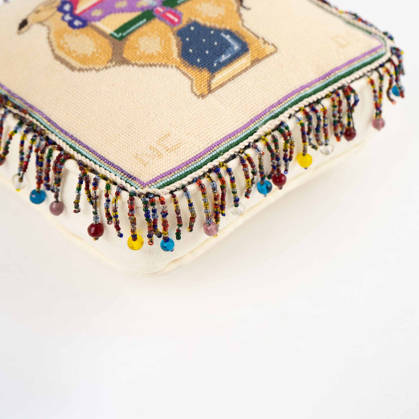 Vintage square needlepoint pillow with hand-stitched camel design and decorative beaded trim around edges