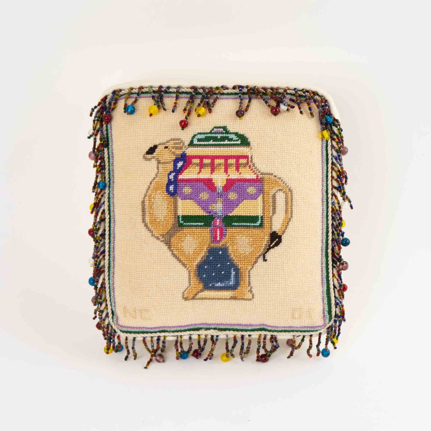 Vintage square needlepoint pillow with hand-stitched camel design and decorative beaded trim around edges