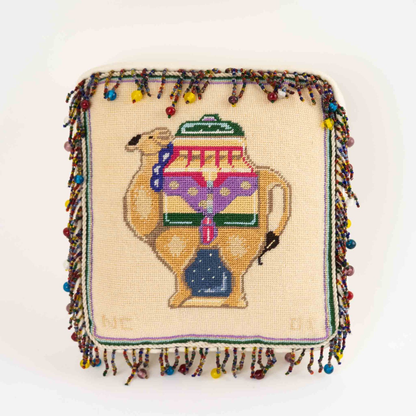 Vintage square needlepoint pillow with hand-stitched camel design and decorative beaded trim around edges
