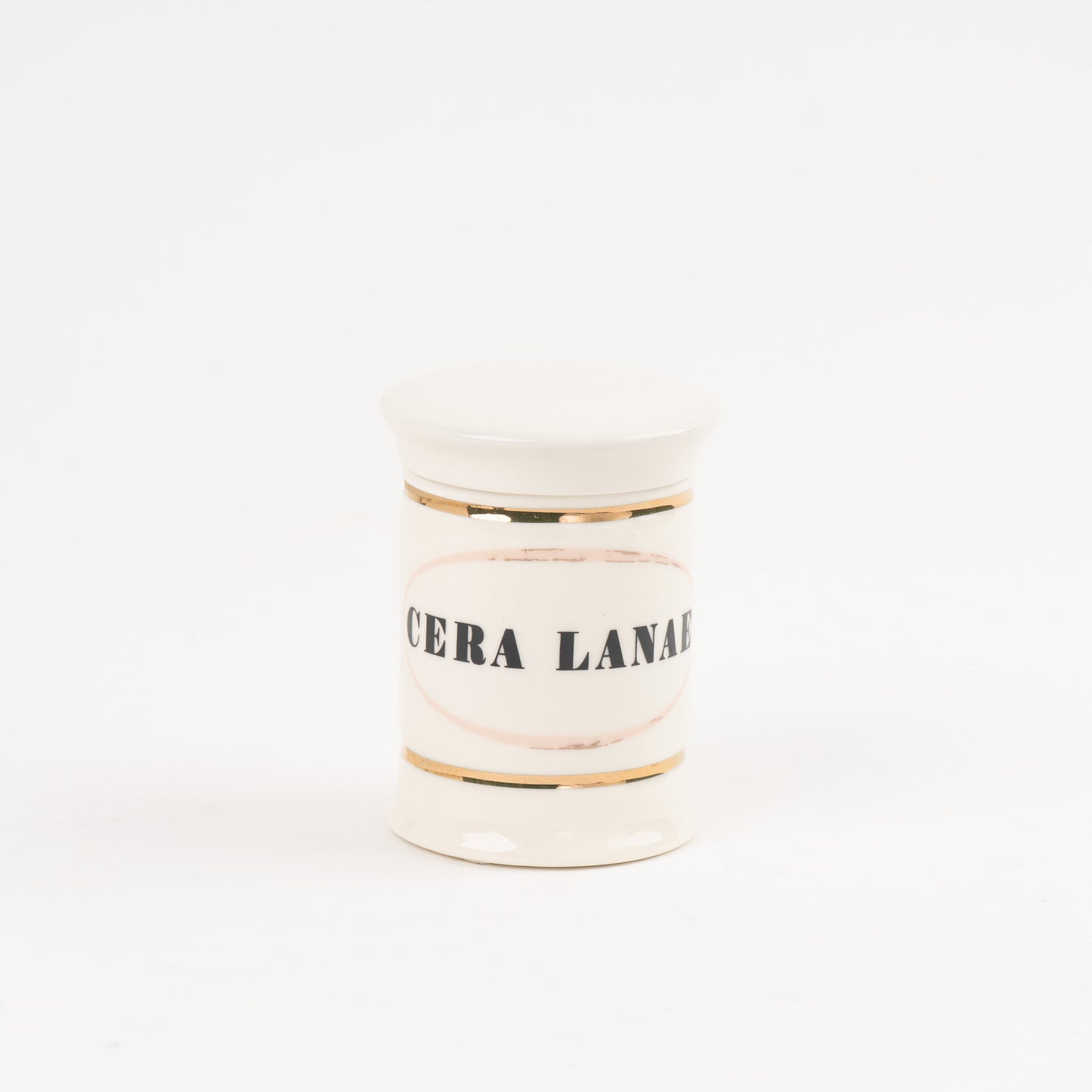 Cera Lanae off-white ceramic apothecary jar with gold accents and vintage pharmaceutical-style lettering, with matching lid