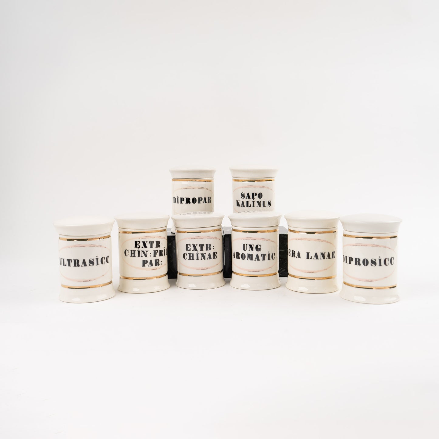 Set of 8 off-white ceramic apothecary jars with gold accents and vintage pharmaceutical-style lettering, each with matching lid