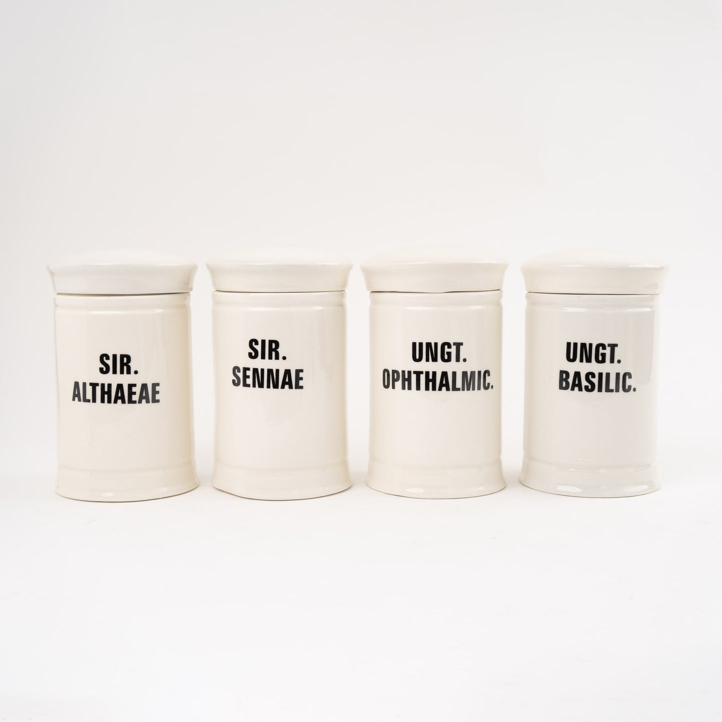 Off-white ceramic apothecary jars with black vintage lettering and matching lids 