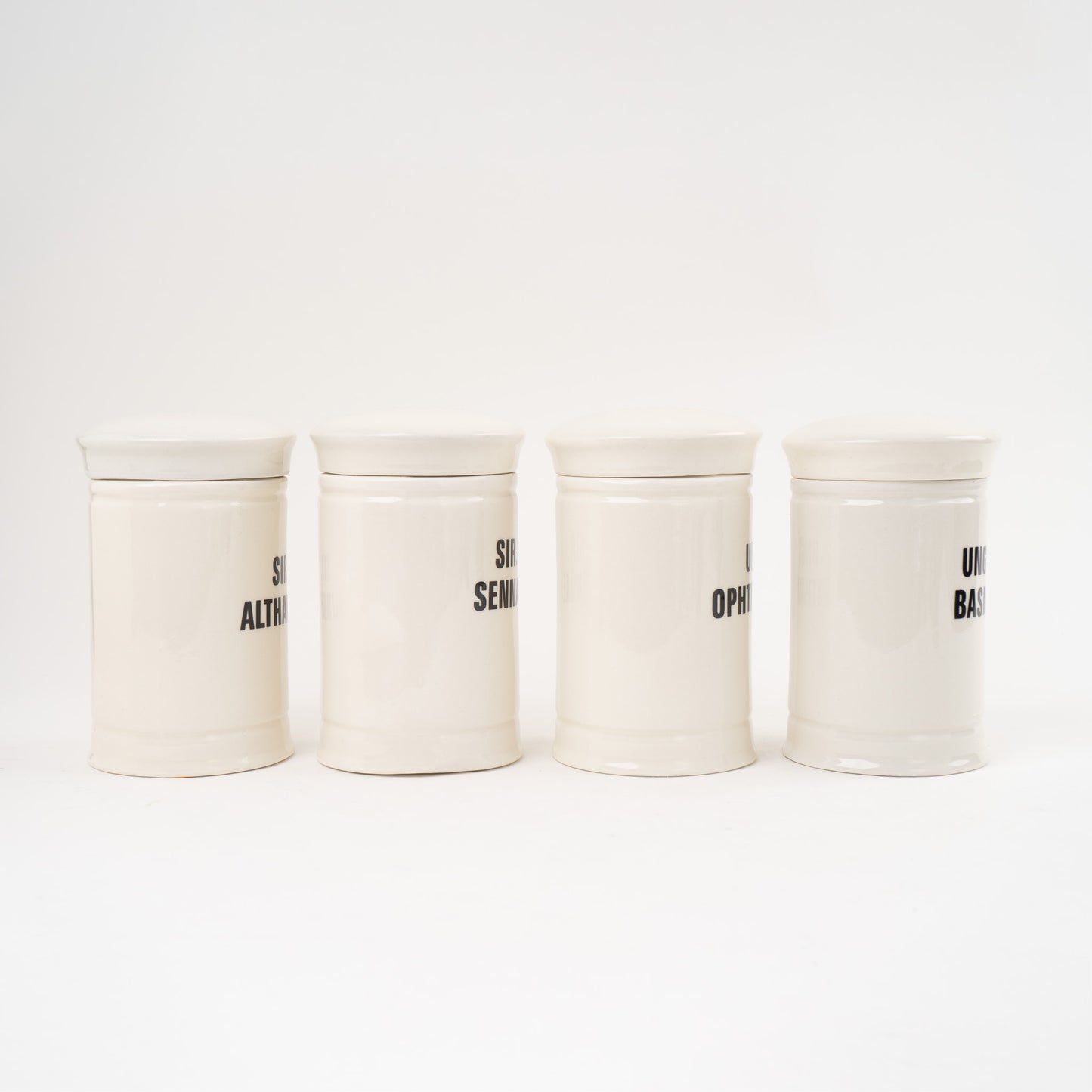 Off-white ceramic apothecary jars with black vintage lettering and matching lids 