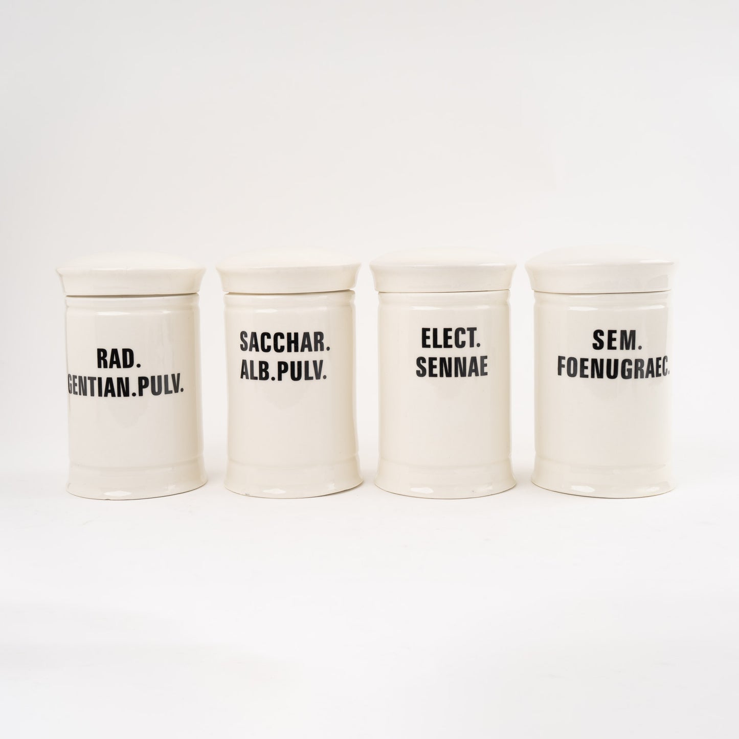 Off-white ceramic apothecary jars with black vintage lettering and matching lids 