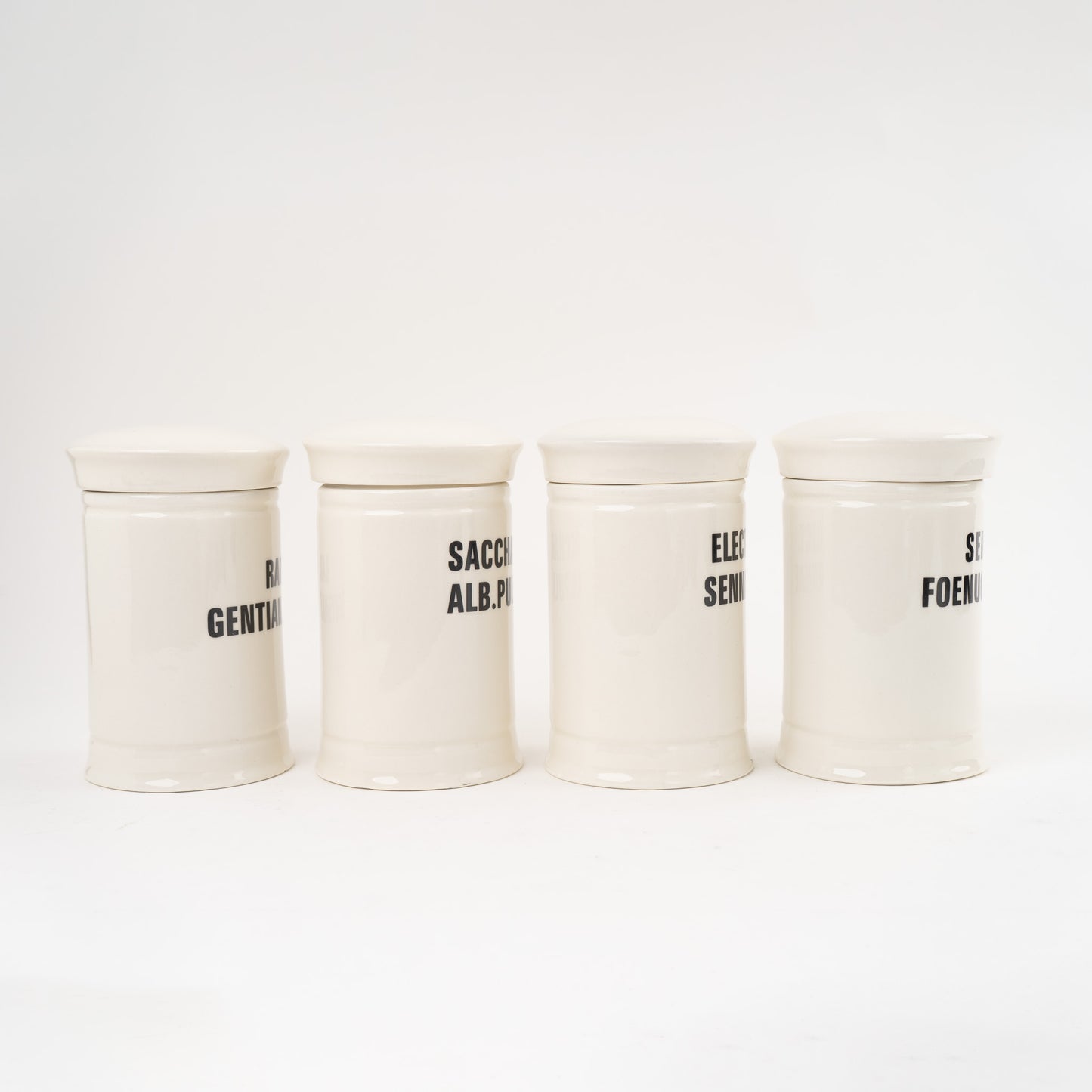 Off-white ceramic apothecary jars with black vintage lettering and matching lids 