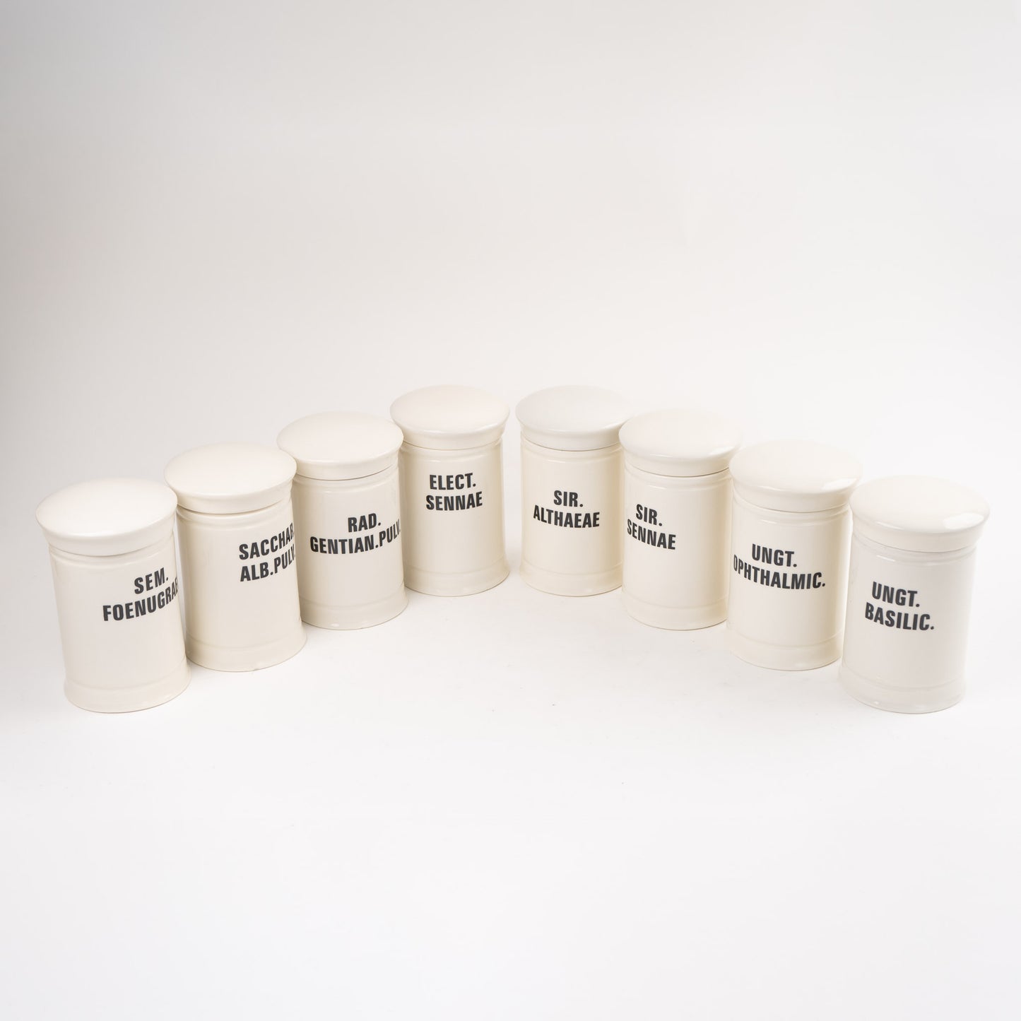 Off-white ceramic apothecary jars with black vintage lettering and matching lids 