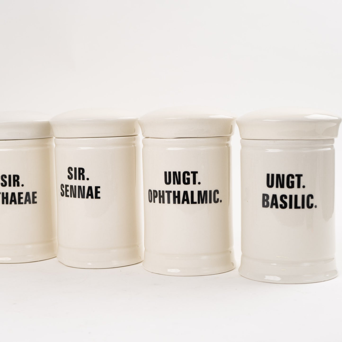 Off-white ceramic apothecary jars with black vintage lettering and matching lids 
