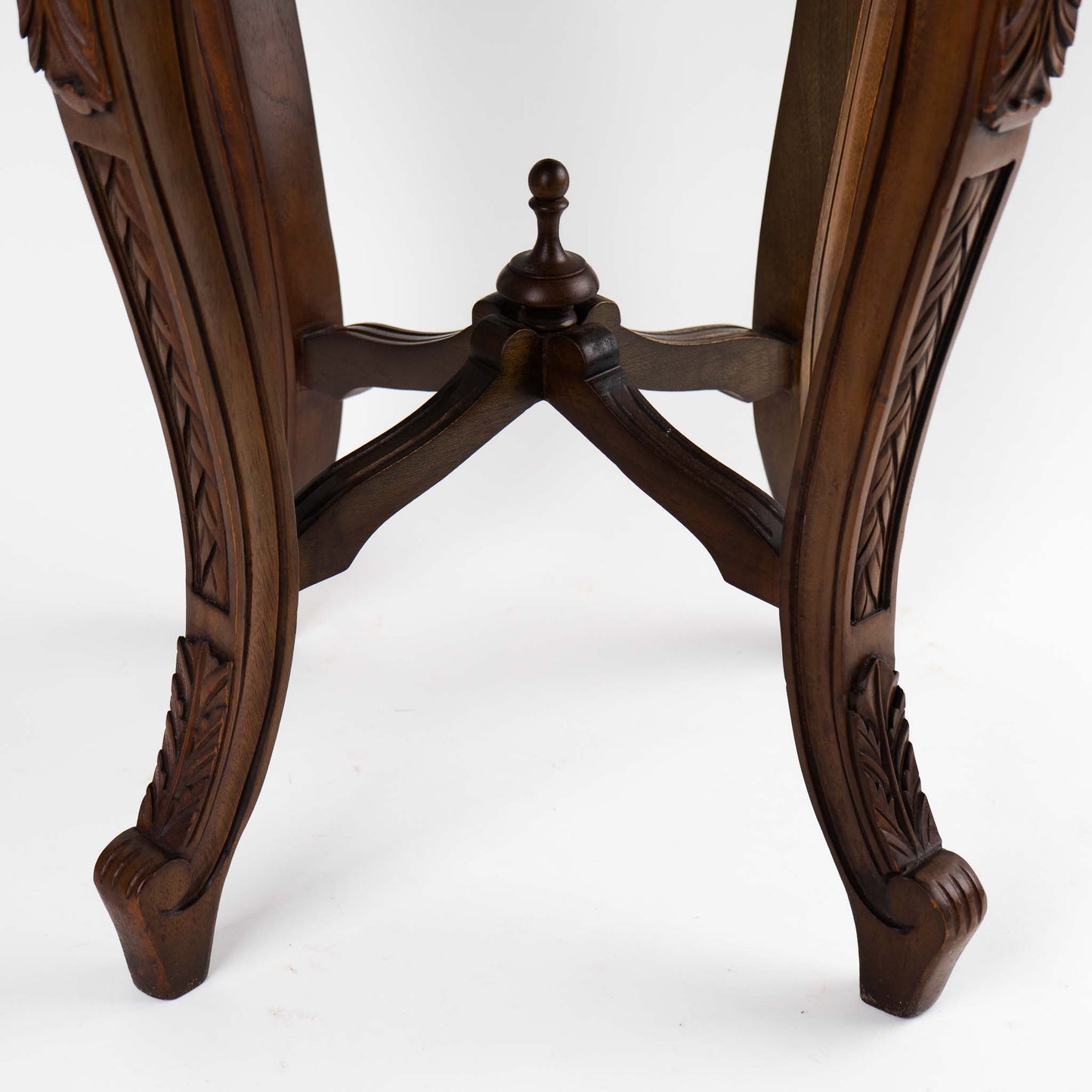 close up of carved details on a vintage mahogany wood side table with round dark black and green marble inlay center piece in French antique style 