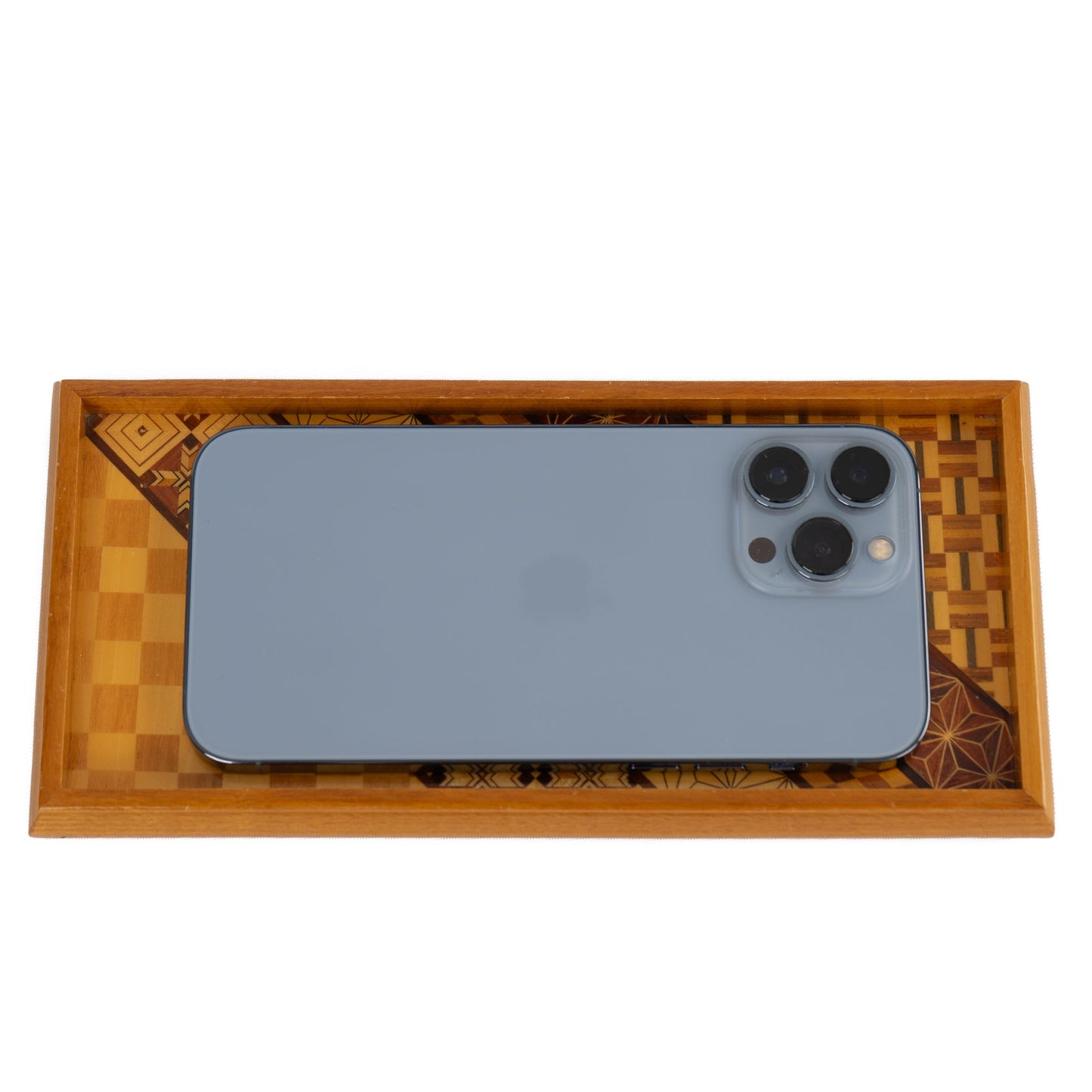 Vintage rectangular wood marquetry tray featuring six geometric patterns with contrasting wood tones and intricate inlay patterns holding an iphone 