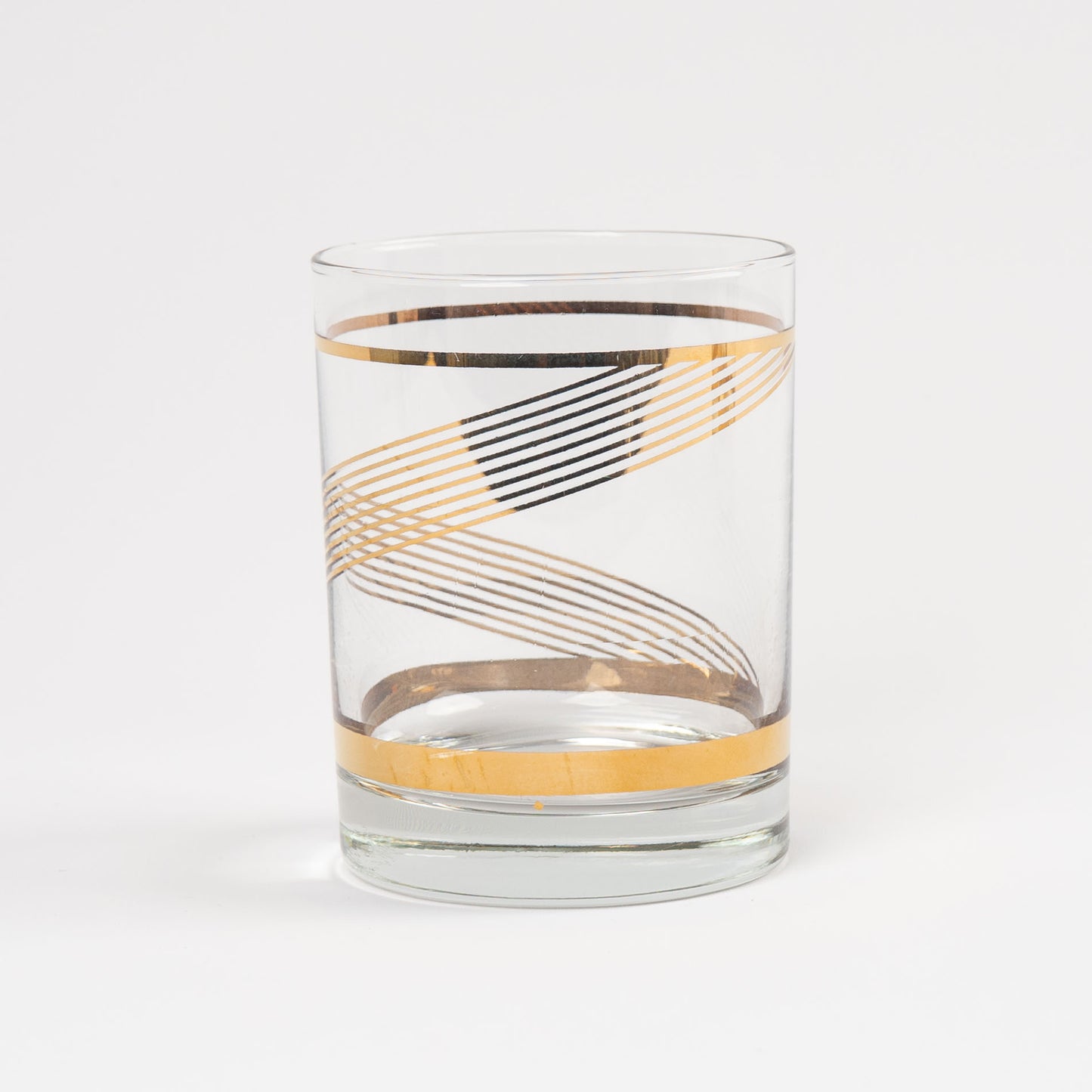 vintage lowball cocktail glass with gold swirl band pattern on clear glass