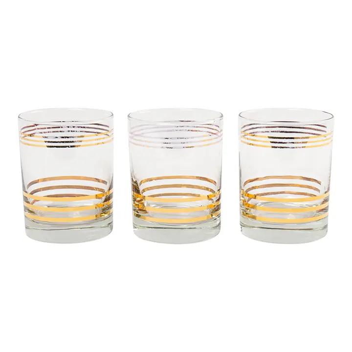 Set of three vintage lowball cocktail glasses with horizontal gold stripes arranged on white background