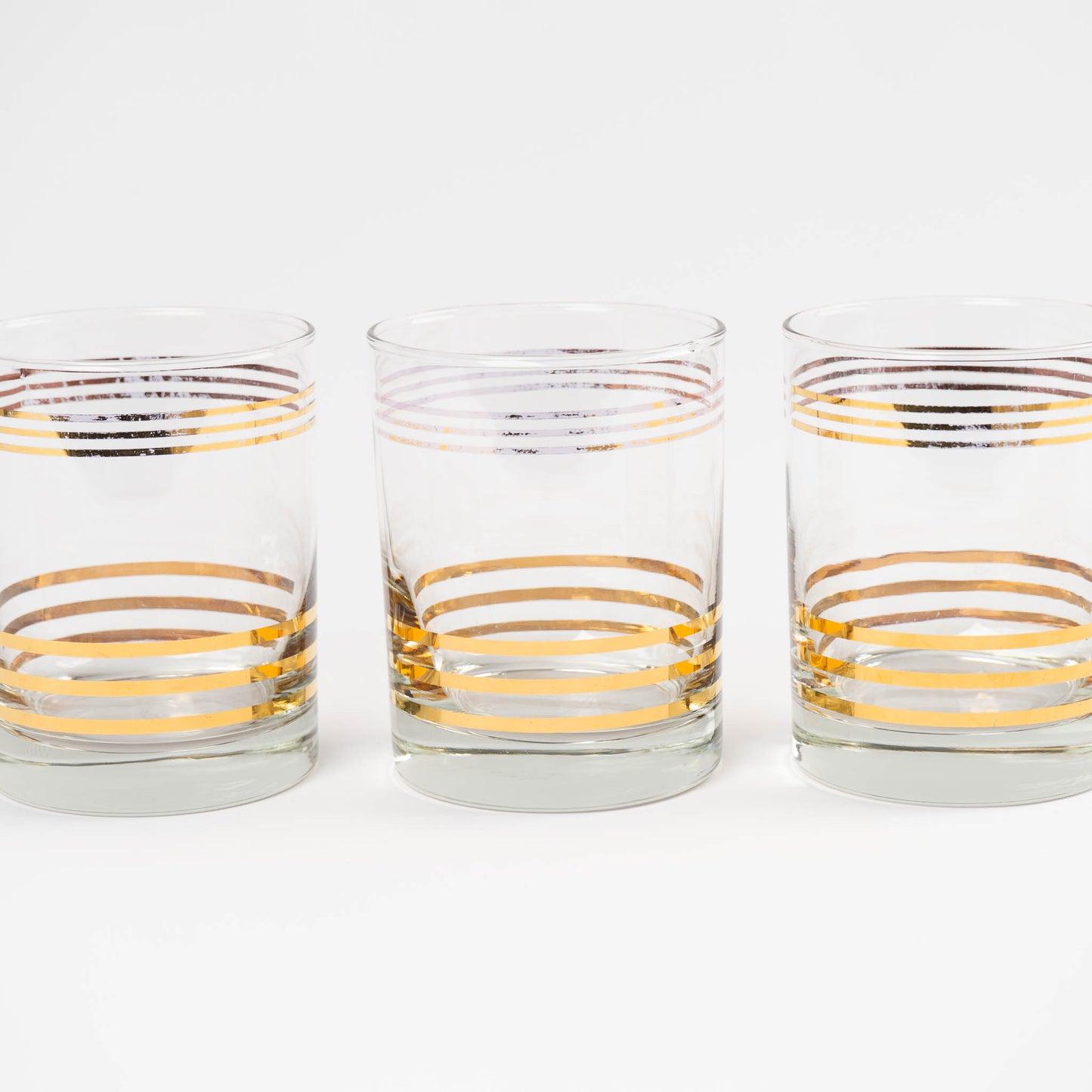 Set of three vintage lowball cocktail glasses with horizontal gold stripes 