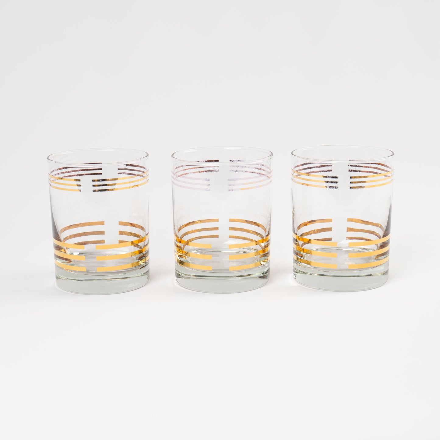 Set of three vintage lowball cocktail glasses with horizontal gold stripes 