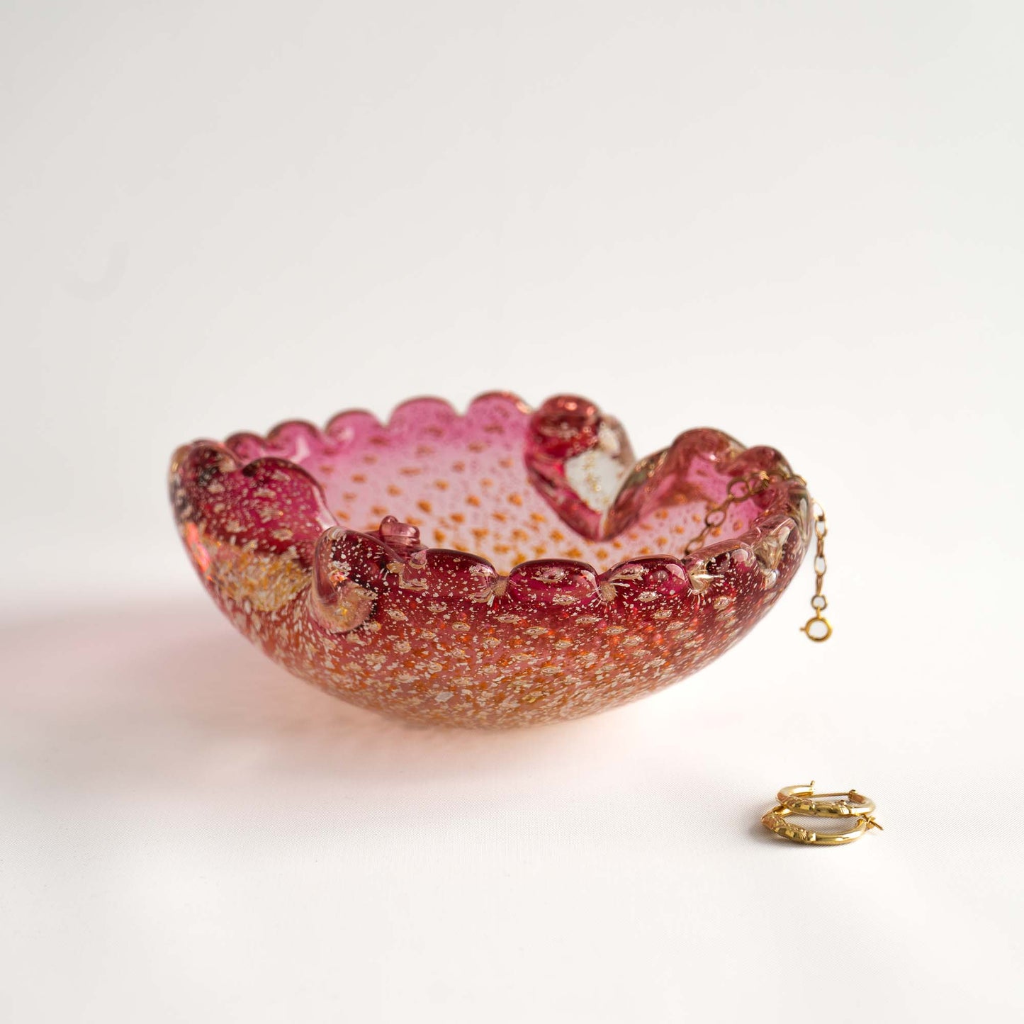 Vintage Murano Bullicante art glass catchall dish in pink and yellow with gold aventurine flecks and scalloped edge, shown as a jewelry holder 