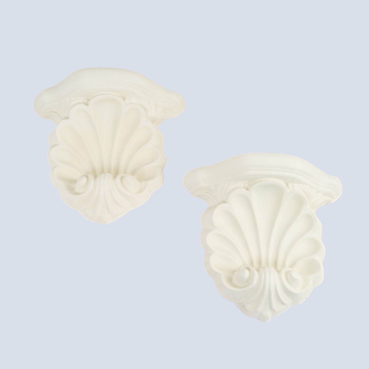 Pair of vintage white plaster shell scroll corbel wall shelves displayed side by side on a light blue wall