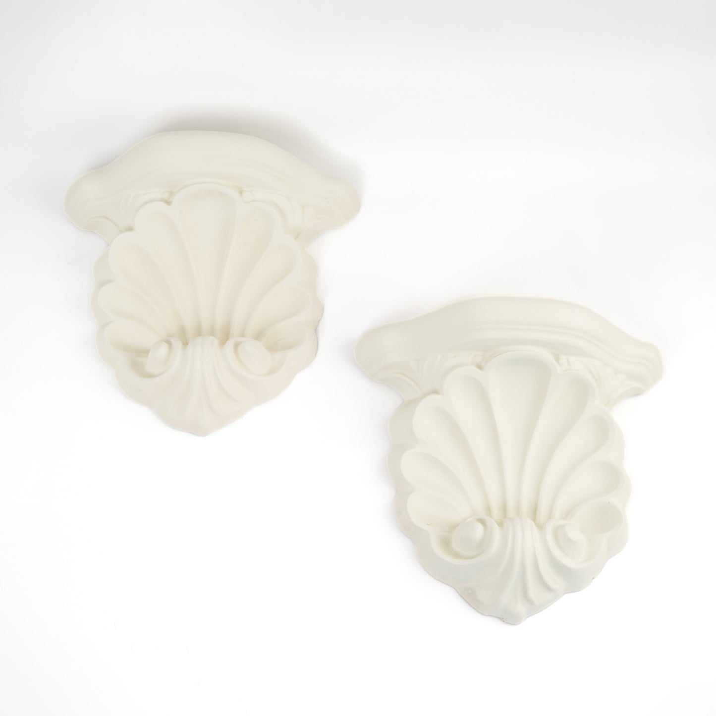 Pair of vintage white plaster shell scroll corbel wall shelves displayed side by side.