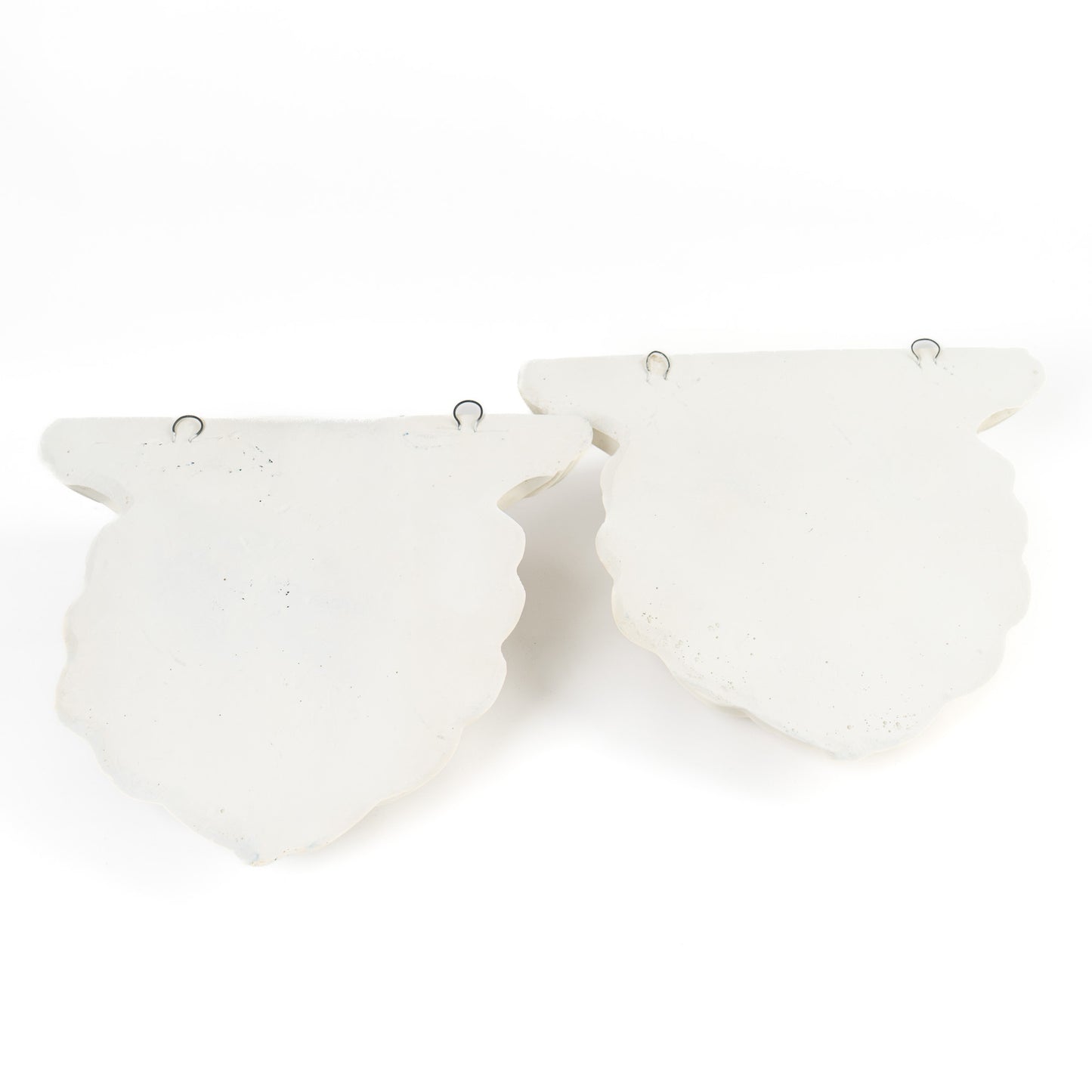 Back of a vintage plaster wall shelf showing two metal mounting hooks