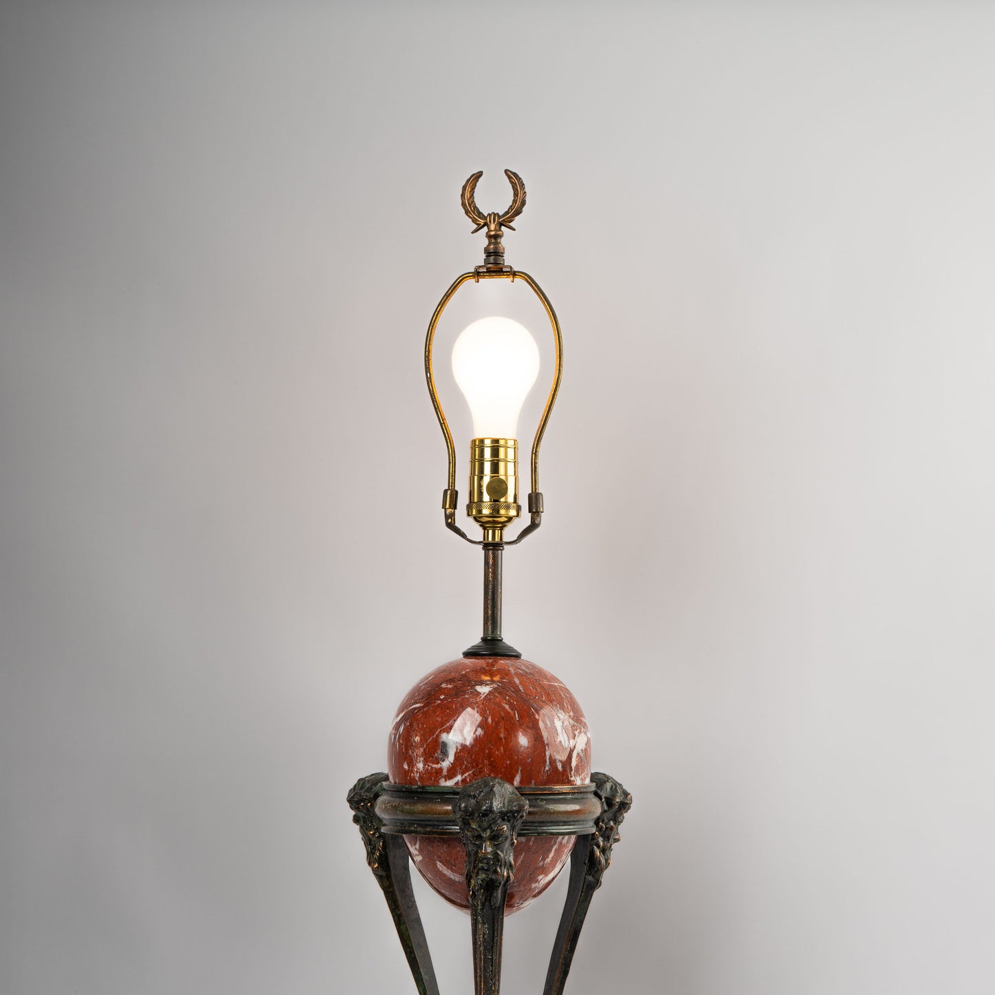 Vintage neoclassical athénienne table lamp with red Italian marble egg orb on dark bronze tripod base lit up with light bulb 