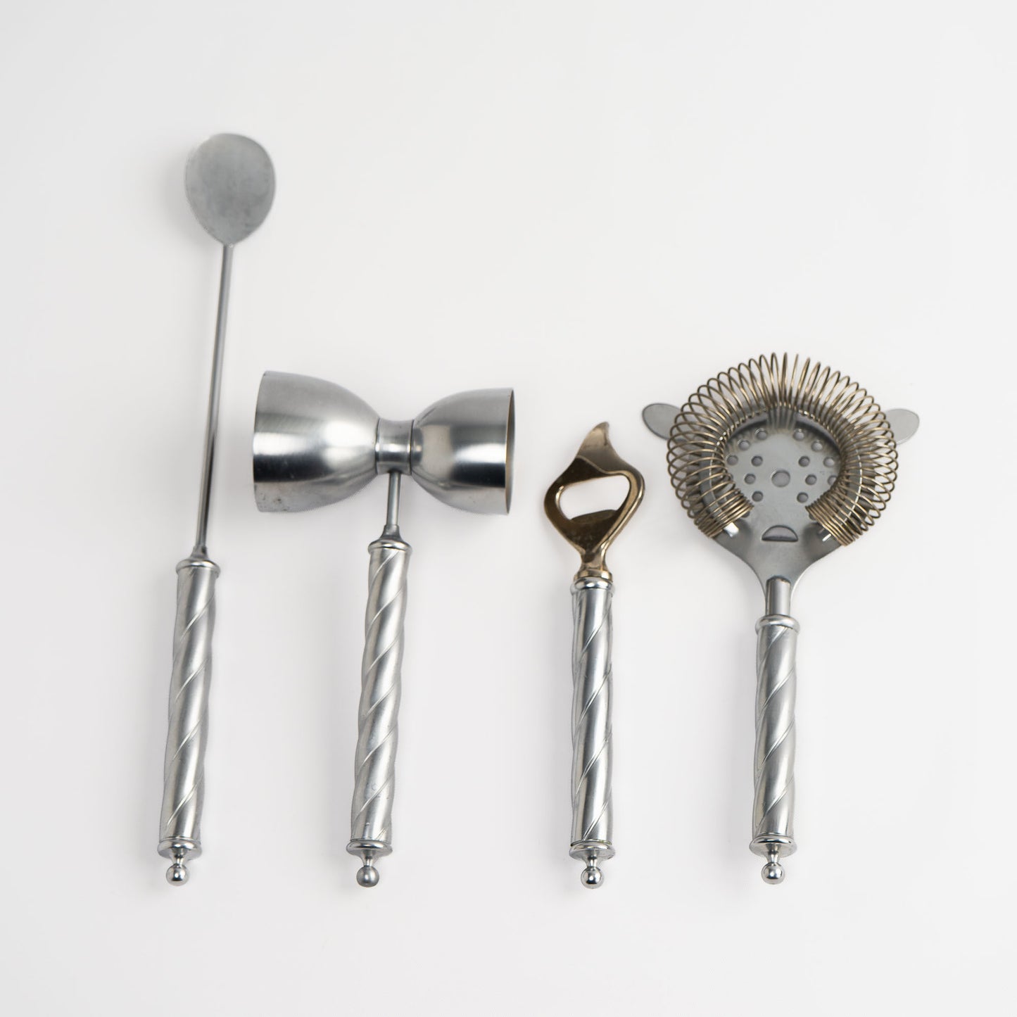 Vintage Italian metal bar tool set of four with twisted handles, including stirring spoon, jigger, bottle opener, and strainer
