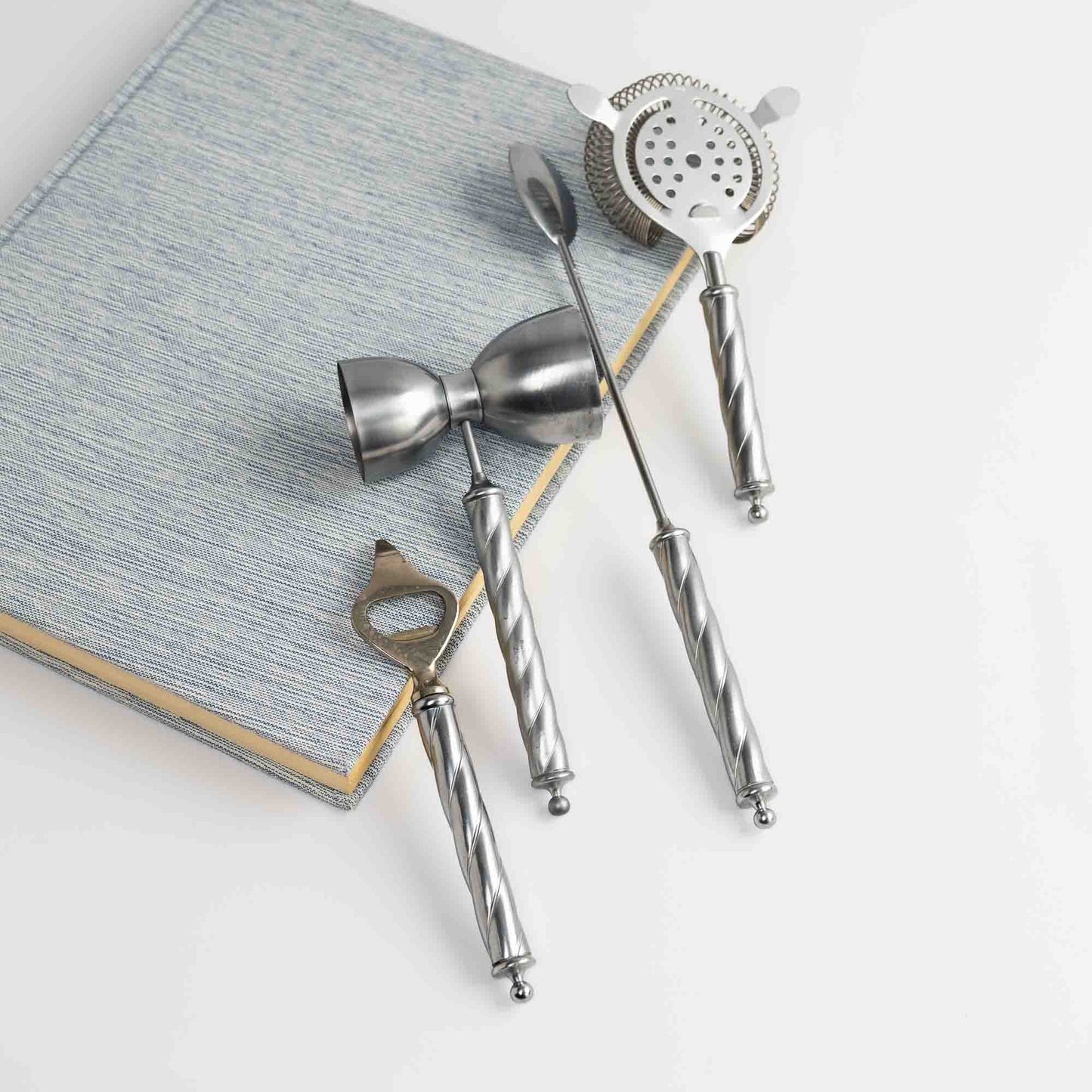 Vintage Italian metal bar tool set of four with twisted handles, including stirring spoon, jigger, bottle opener, and strainer 