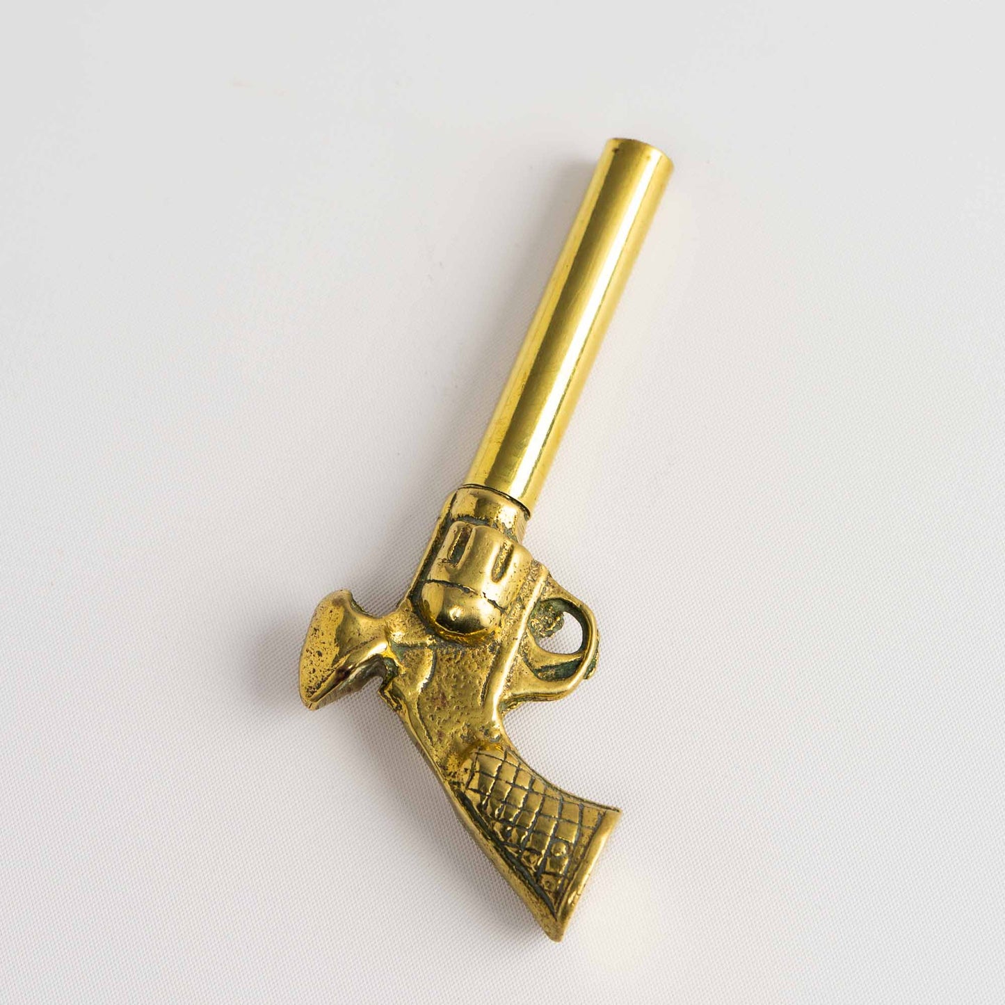 Vintage brass revolver-shaped corkscrew bottle opener shown fully assembled, displaying detailed cast metalwork and warm patina