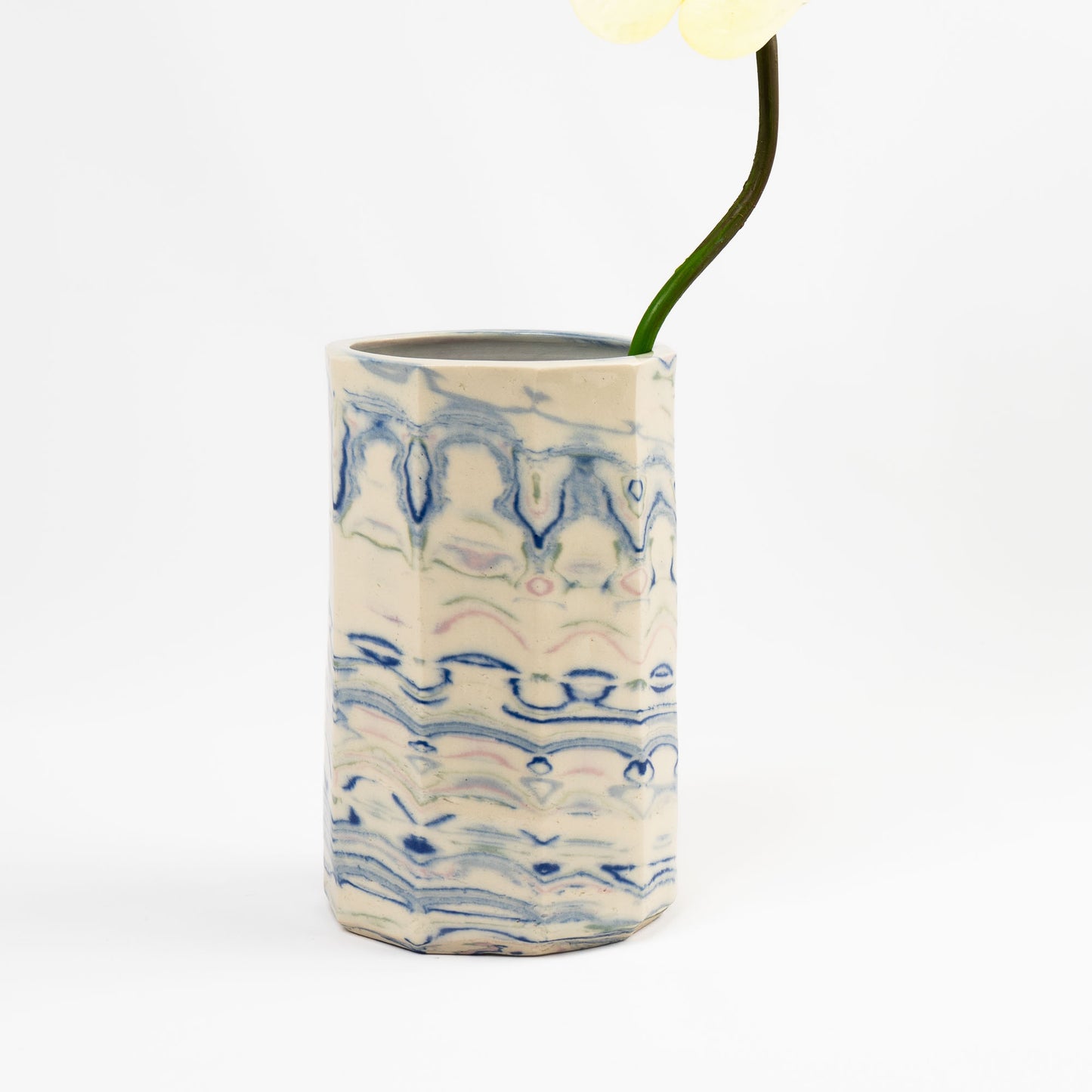 Vintage cylindrical Nerikomi marbled ceramic vase with swirling blue, green, and pink tones on an off-white ground, signed and dated 1982.