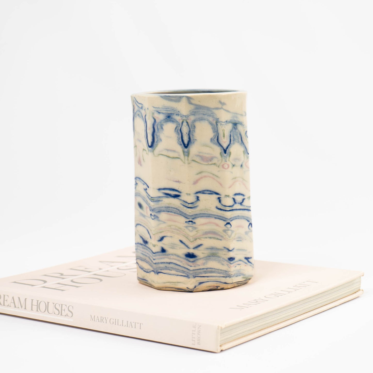 Vintage cylindrical Nerikomi marbled ceramic vase with swirling blue, green, and pink tones on an off-white ground, signed and dated 1982.