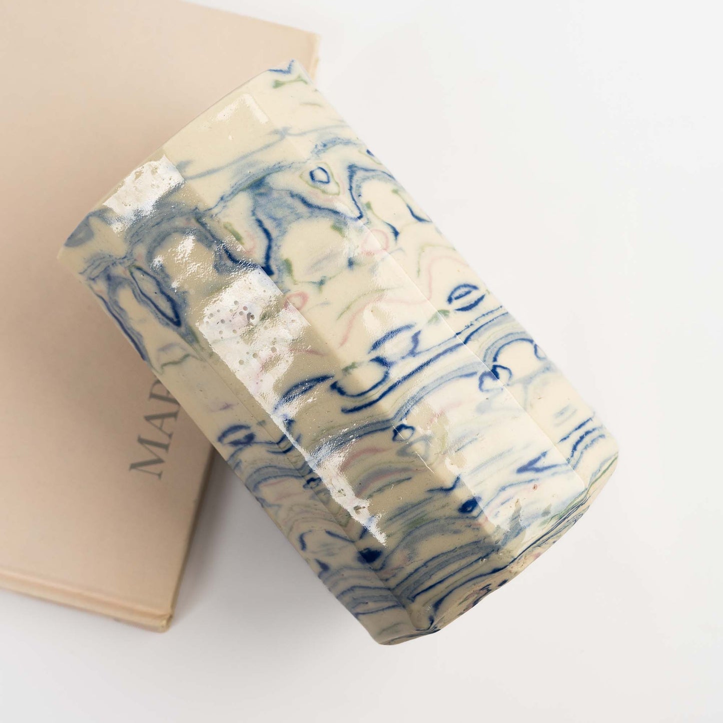 close-up of Nerikomi marbling technique showing layered swirls of blue, green, and pink in a handcrafted ceramic vase.