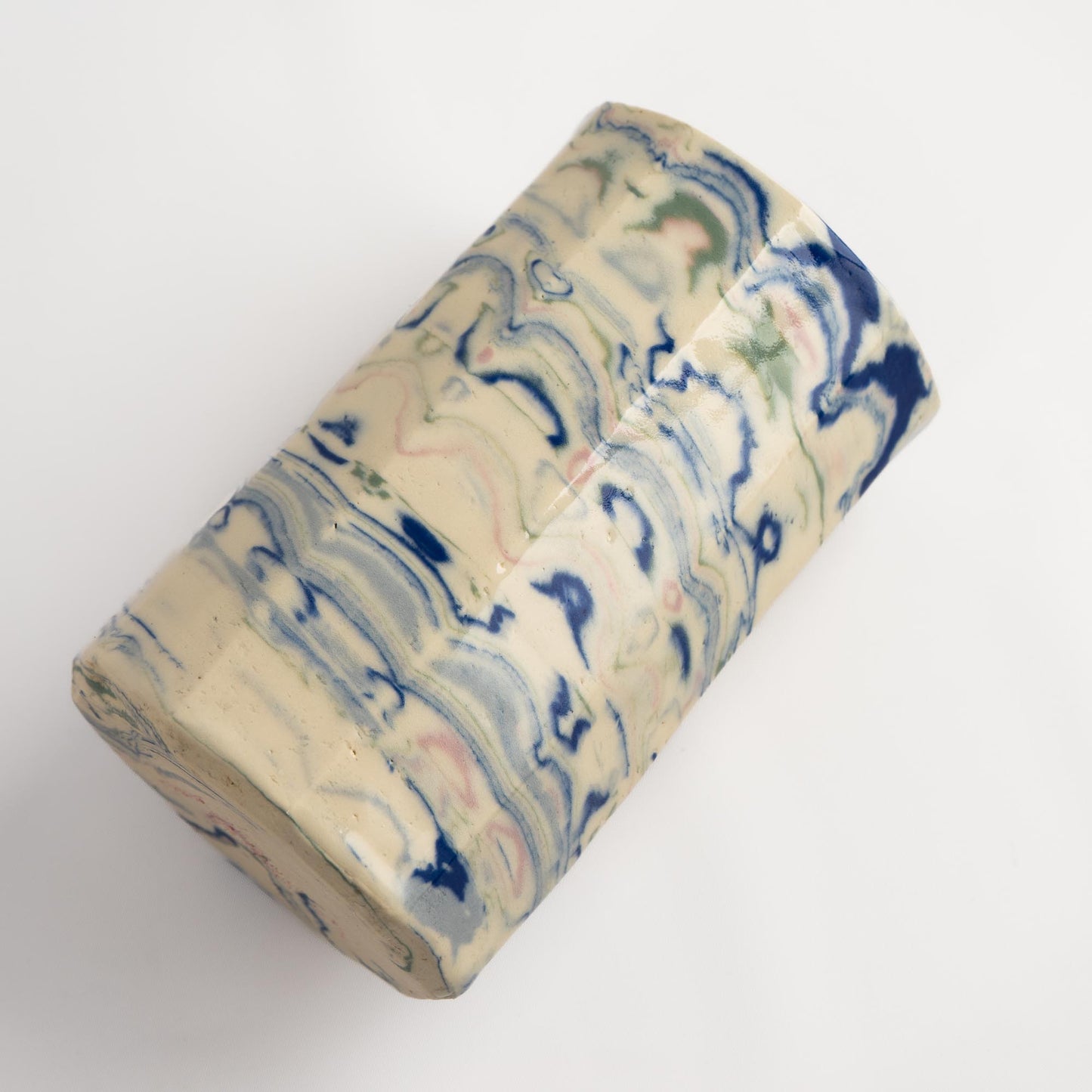 close-up of Nerikomi marbling technique showing layered swirls of blue, green, and pink in a handcrafted ceramic vase.